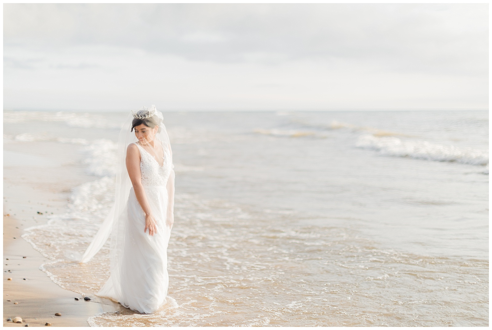 Bride wades into water on Traverse City beach during Northern Michigan beach wedding.