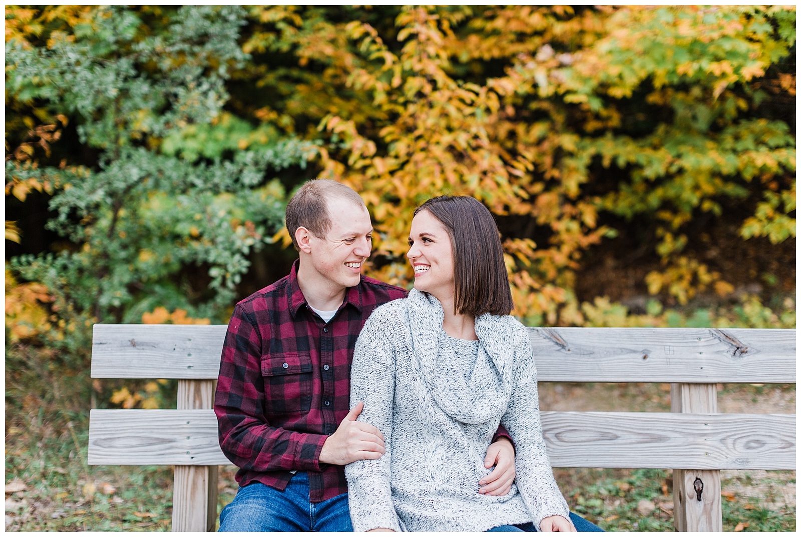 Couple smiles at each other during fall engagement session in Traverse City, Michigan.