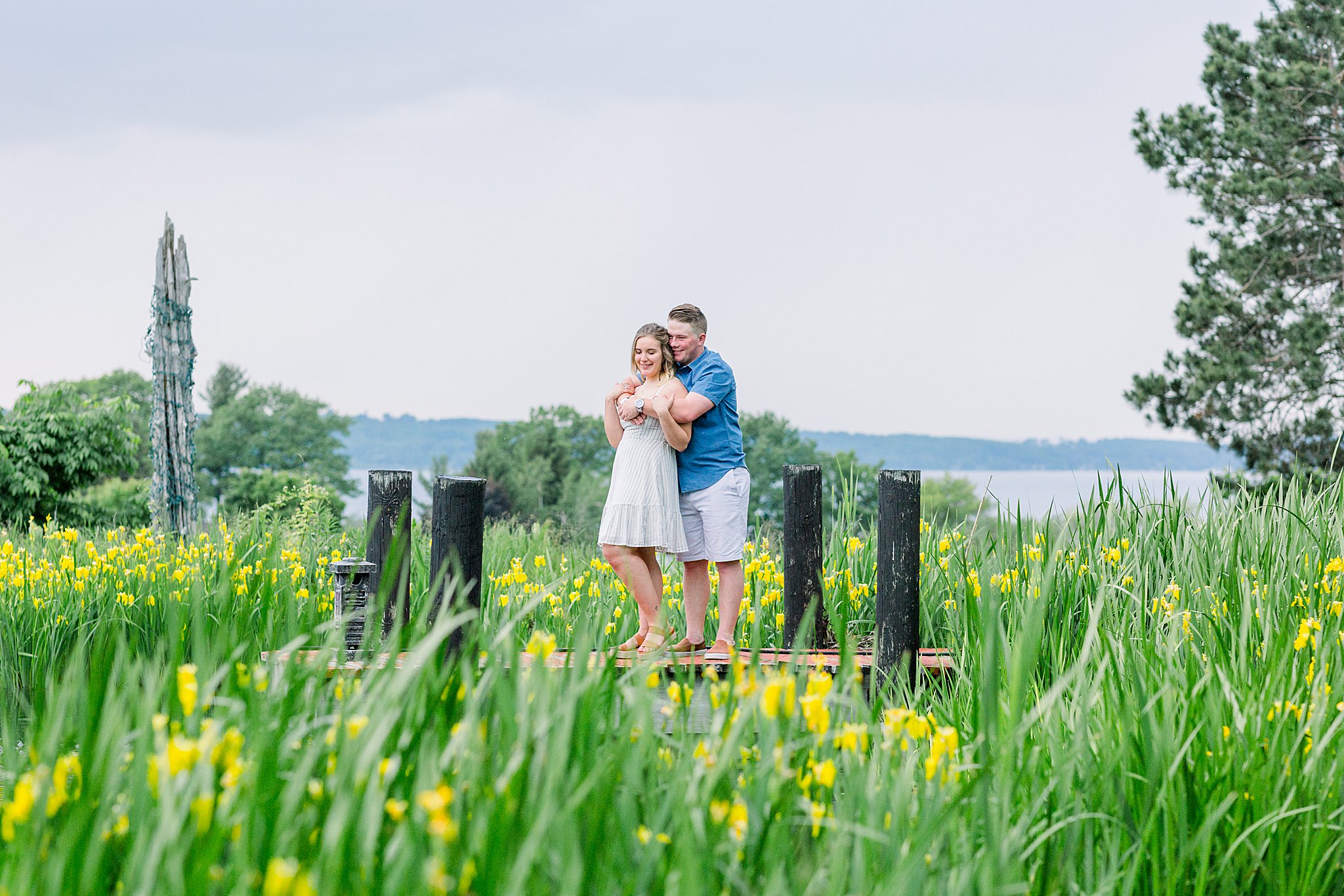 Couple hugs on a dock during Grand Traverse Bay engagement session.