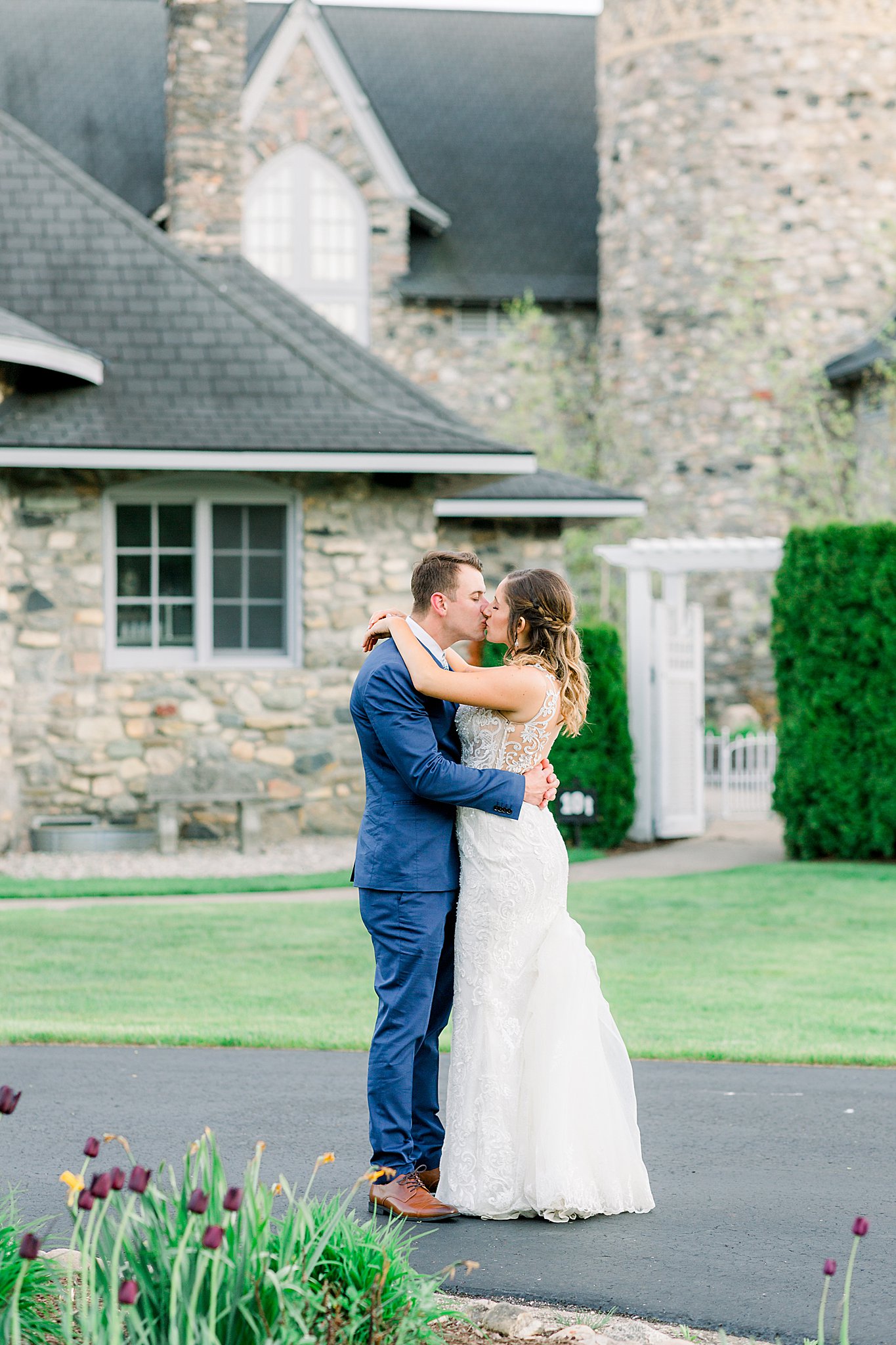 Groom kisses bride in front of Castle Farms gardens during Spring Castle Farms wedding.