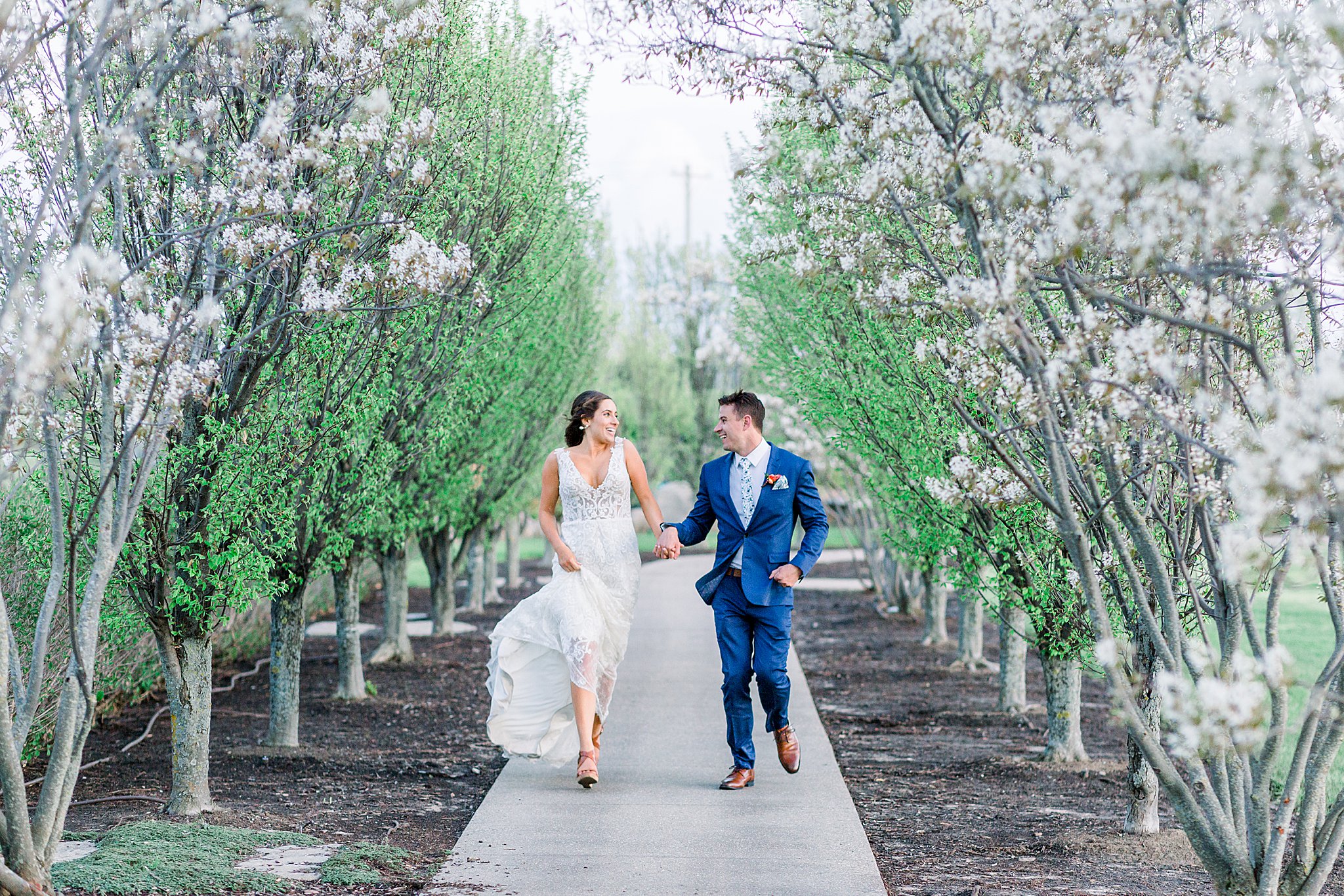 Bride and Groom run through cherry blossoms at Spring Castle Farms wedding.