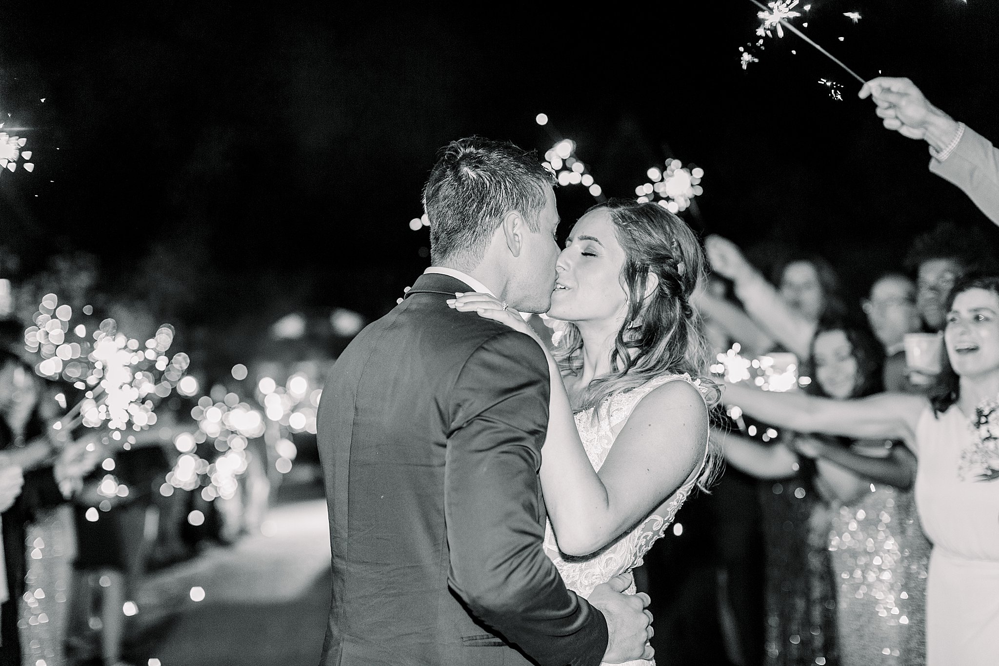 Black and white image of couple kissing during sparkler exit at spring Castle Farms wedding.