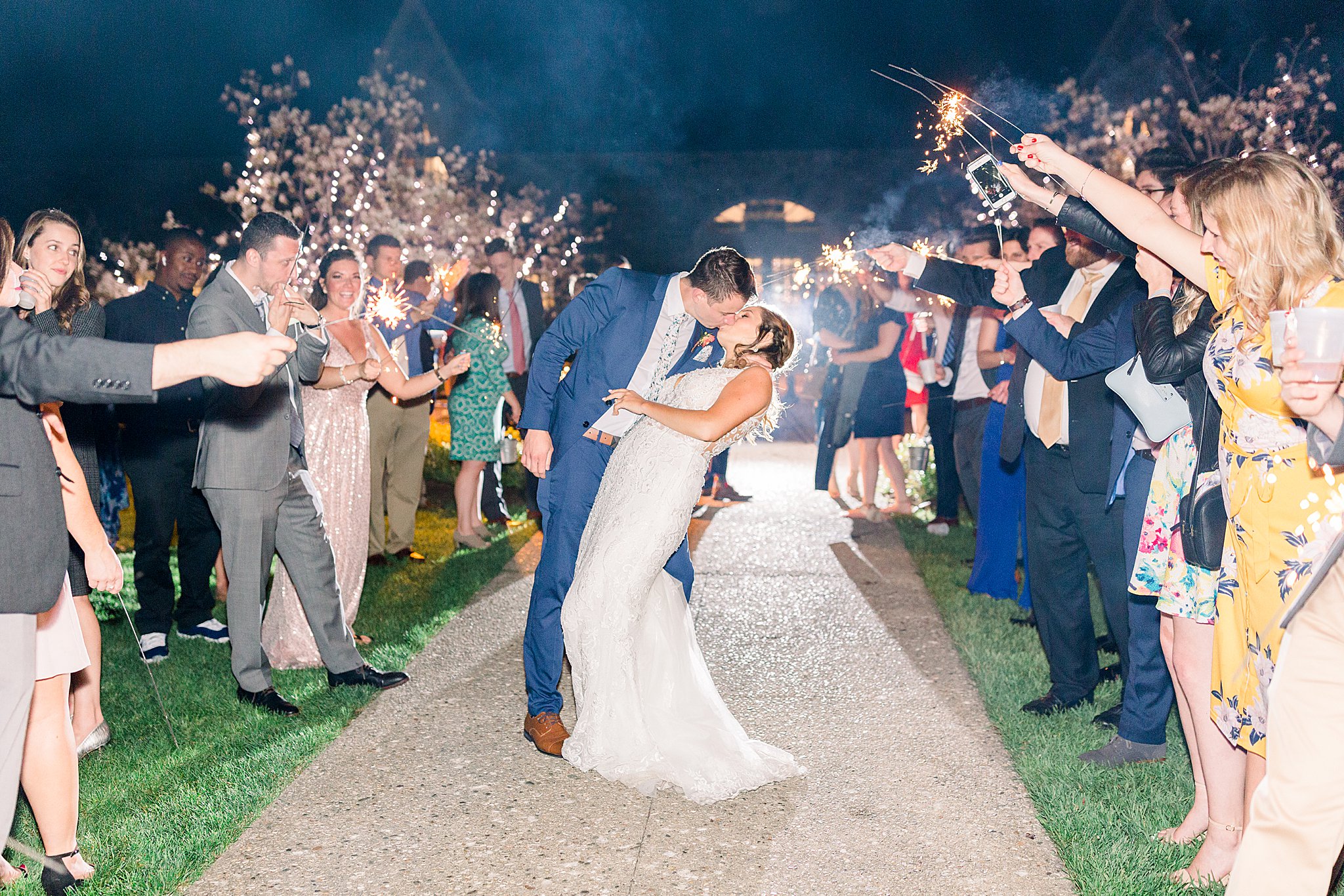 Groom dips bride and kisses her during sparkler exit at spring Castle Farms wedding.