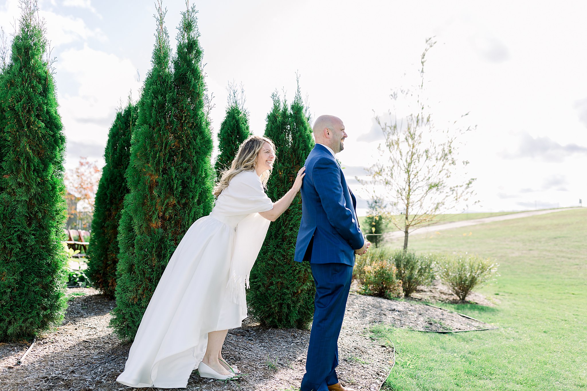 Bride taps groom on shoulder during first look at Aurora Cellars wedding.