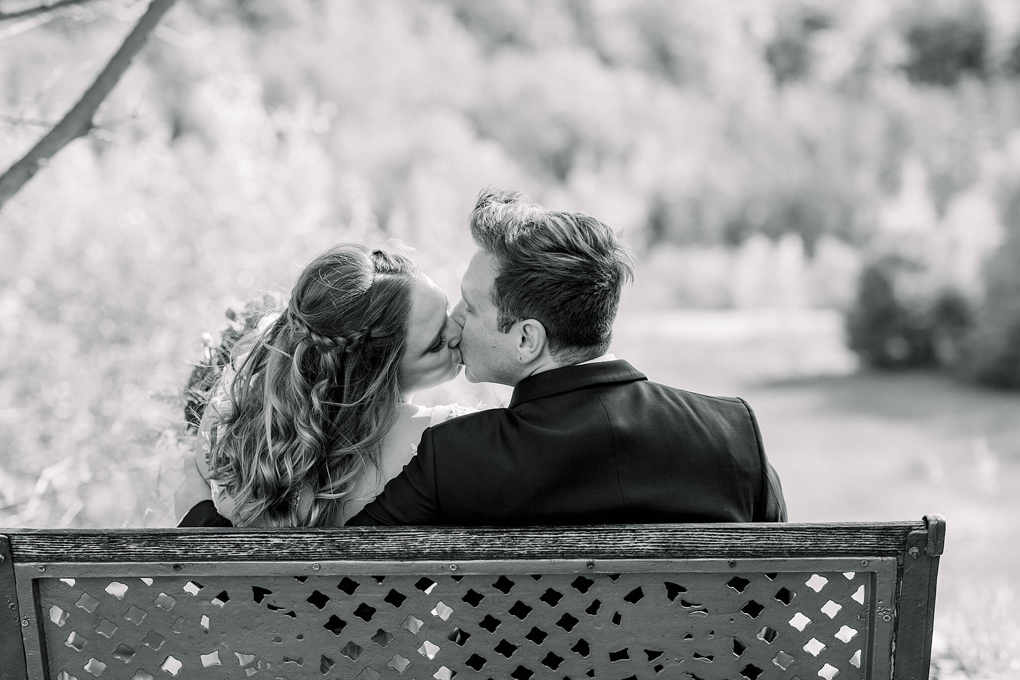 Bride and Groom kiss on bench during Timberlee Hills Wedding in Traverse City, Northern Michigan.