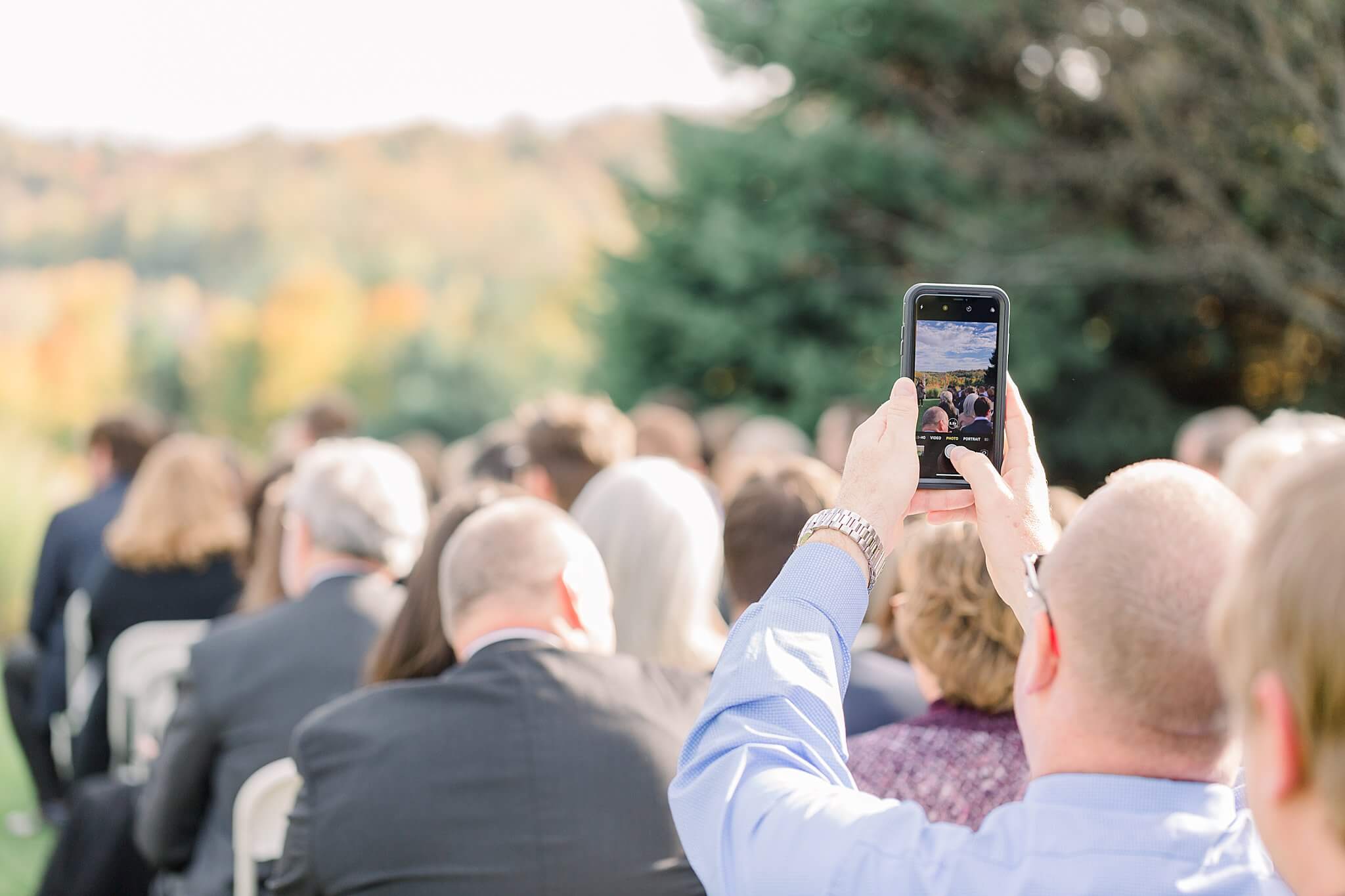 Guest takes picture during ceremony at Timberlee Hills Wedding in Traverse City, Northern Michigan.