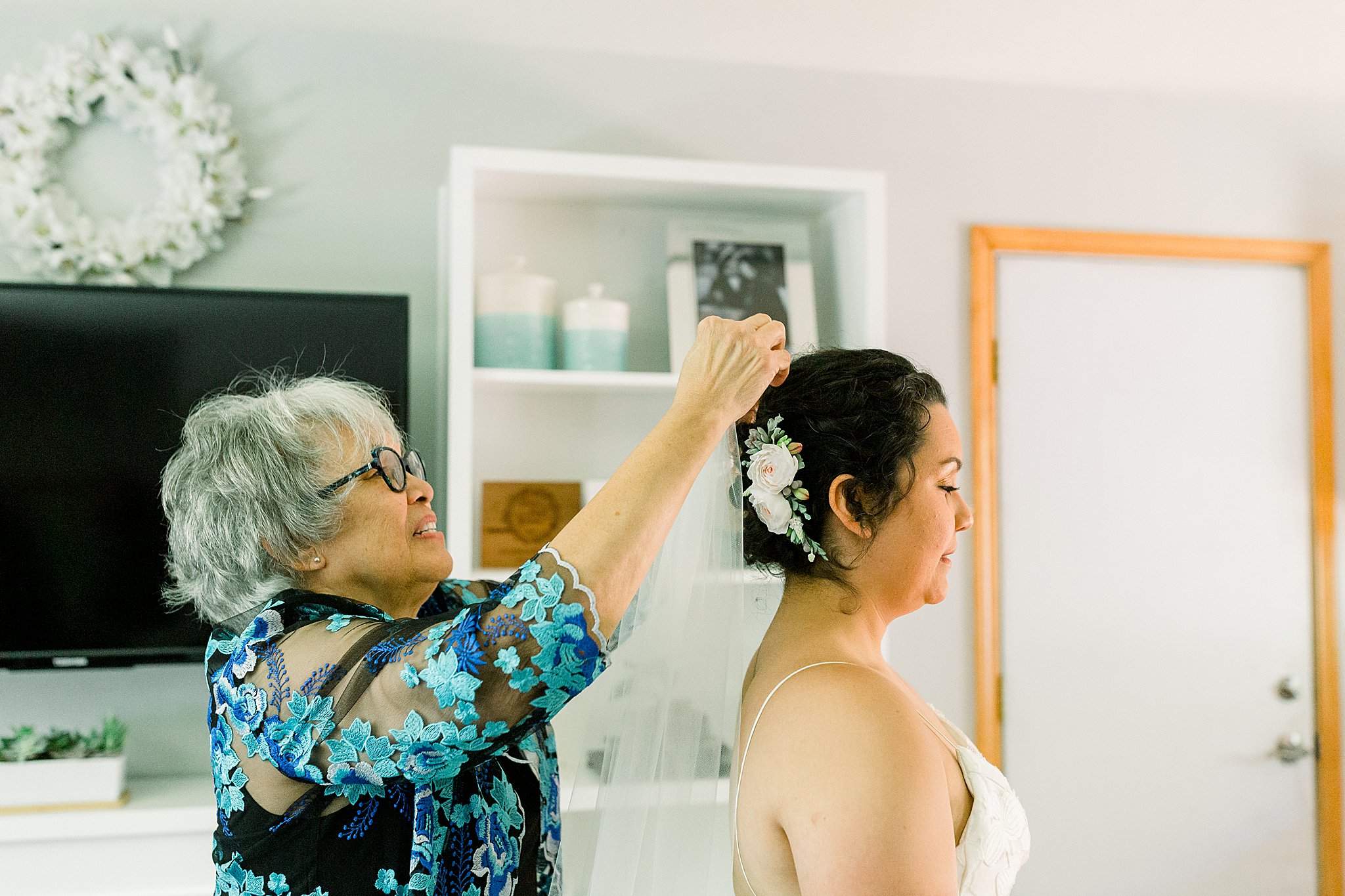 Mother of the bride puts veil in bride's hair while she gets ready for Northern Michigan Intimate Wedding
