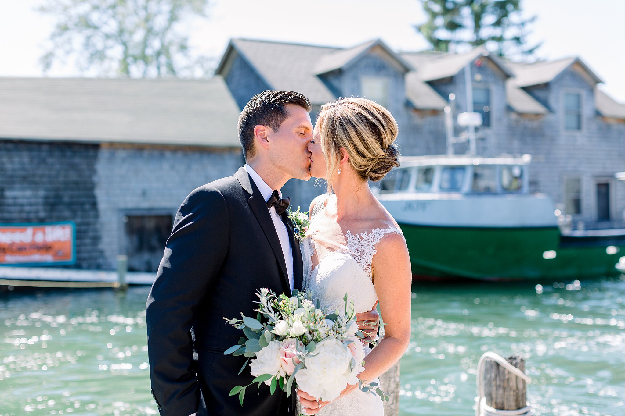 Bride and groom kiss on the docks in Fishtown in Leland during intimate Lake Michigan wedding.