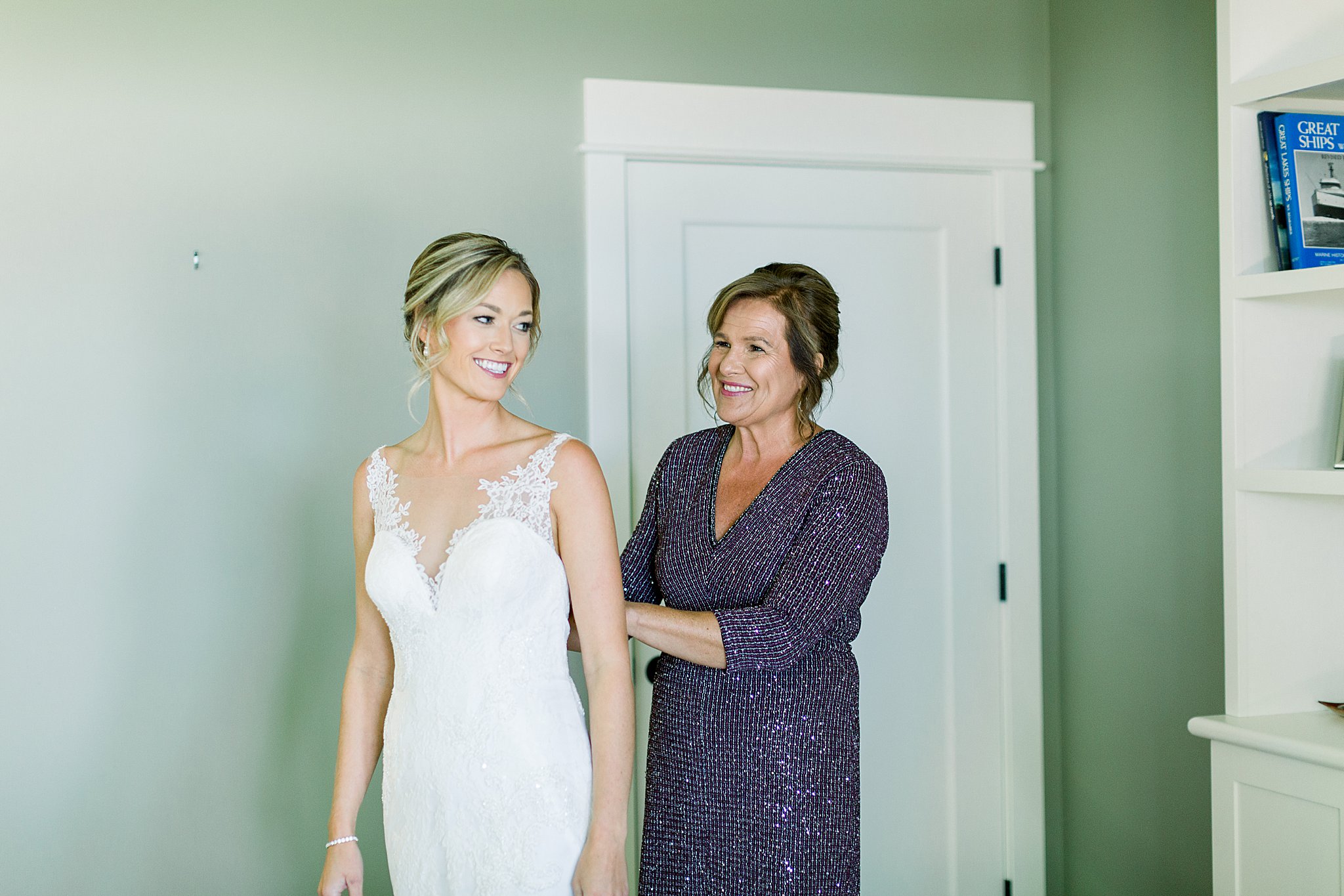 Mother helping bride get dressed for her intimate Lake Michigan wedding.
