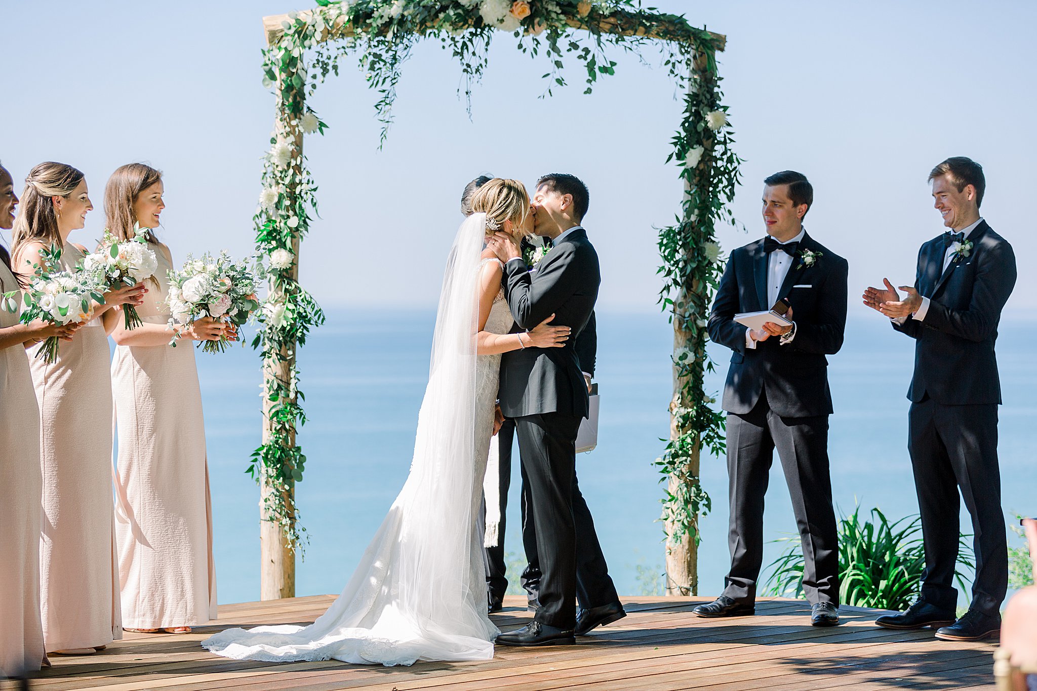 Bride and groom share first kiss during intimate Lake Michigan wedding ceremony.