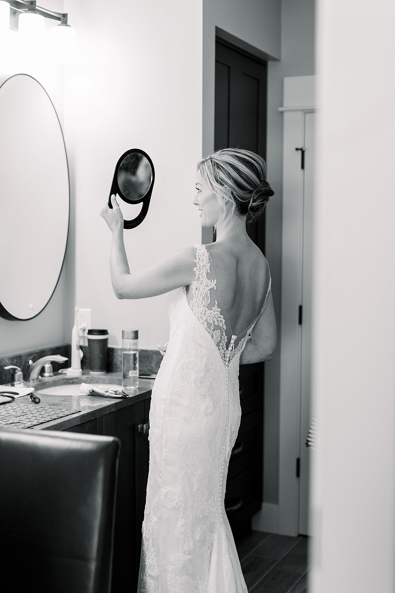Black and white image of bride checking her makeup in the mirror before her intimate Lake Michigan wedding.