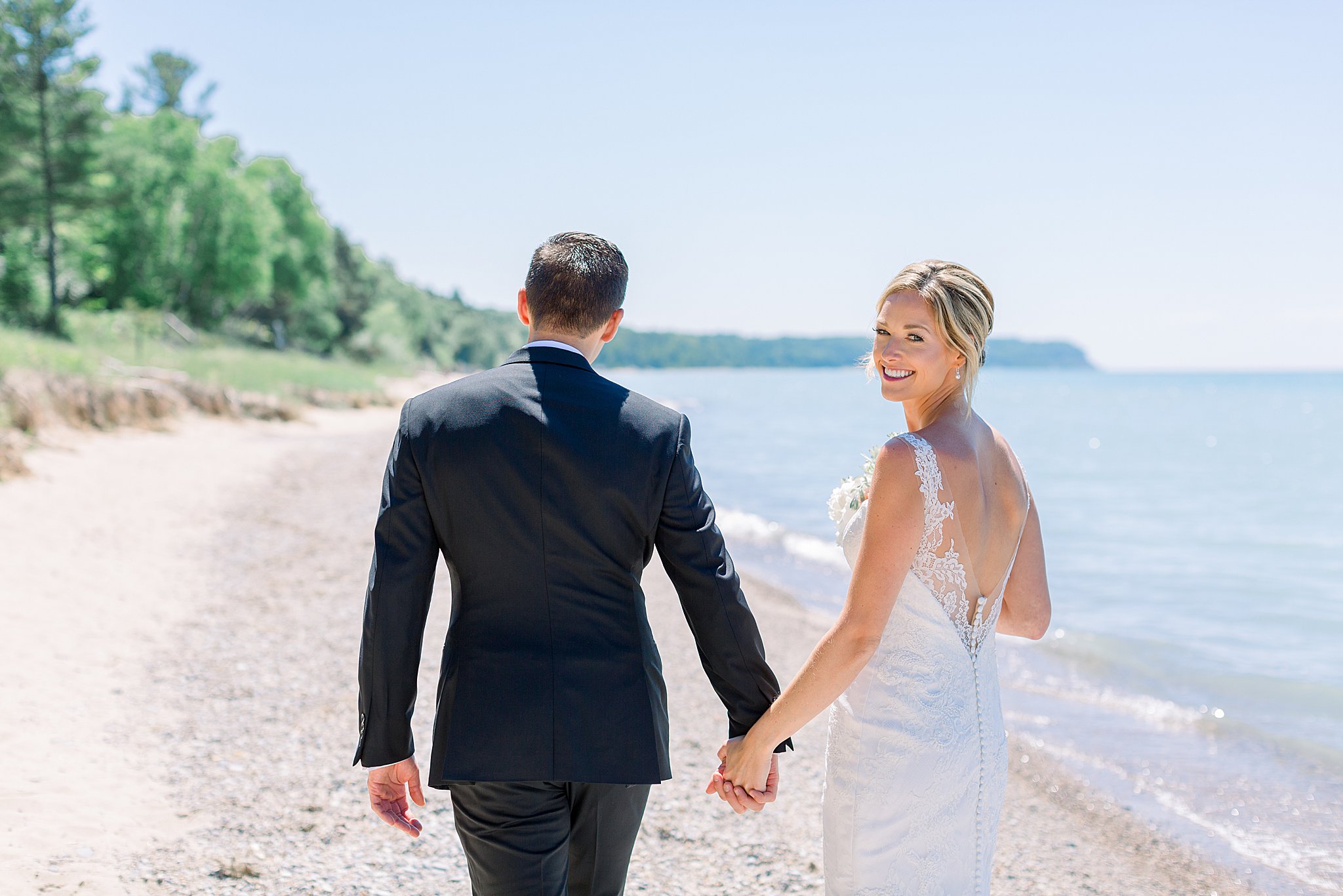 Bride and groom walking along the lakeshore during intimate Lake Michigan wedding.
