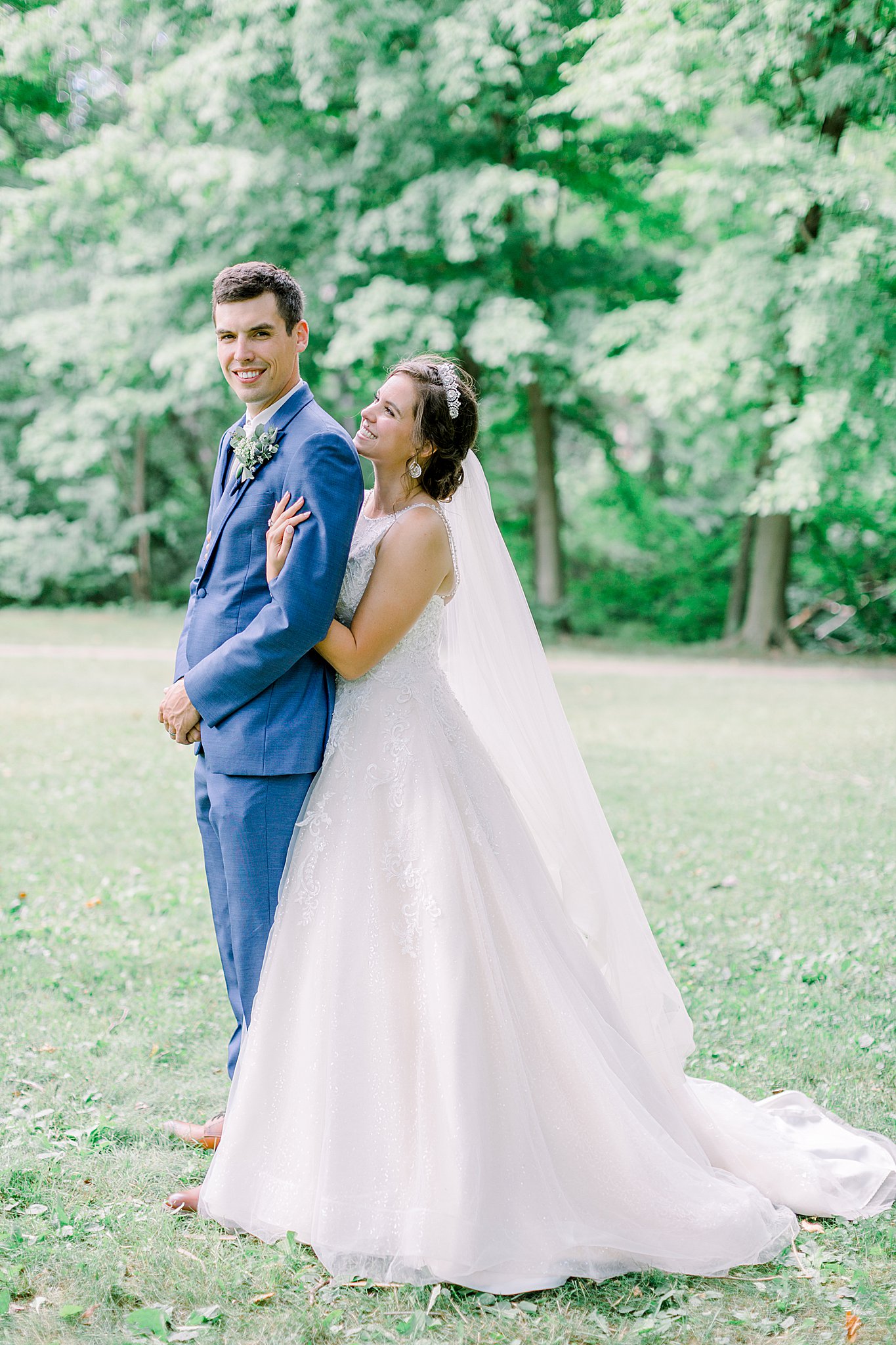 Bride wraps arms around groom and smiles up at him during Michigan July wedding.