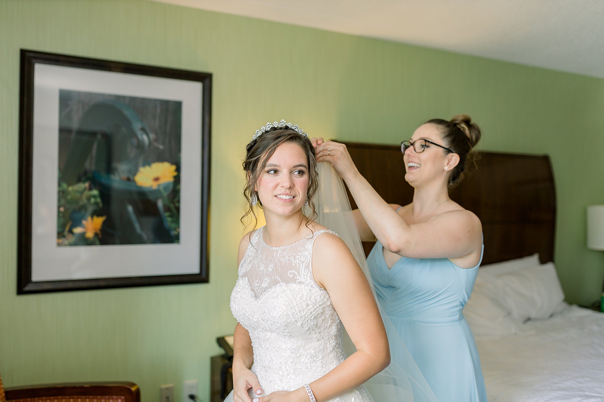 Bride's sister helps her put in veil for her Michigan July wedding.