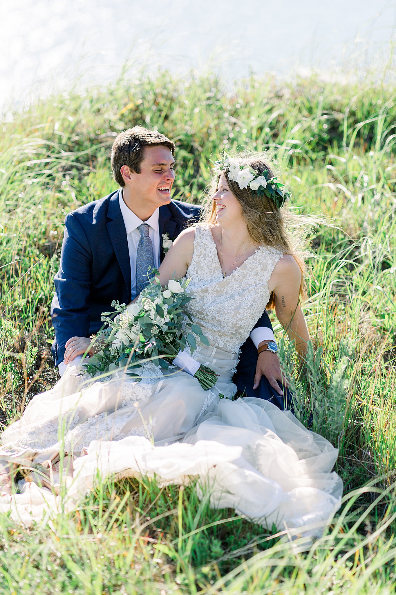 Bride and groom sit in Lake Michigan grass on sand dunes during Northern Michigan elopement.