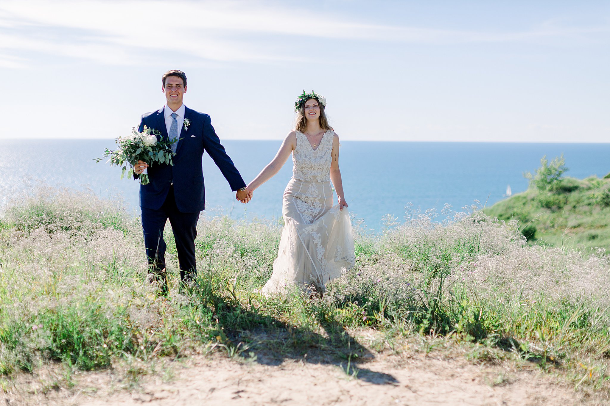 Bride and groom walk holding hands near Lake Michigan during Northern Michigan elopement. 