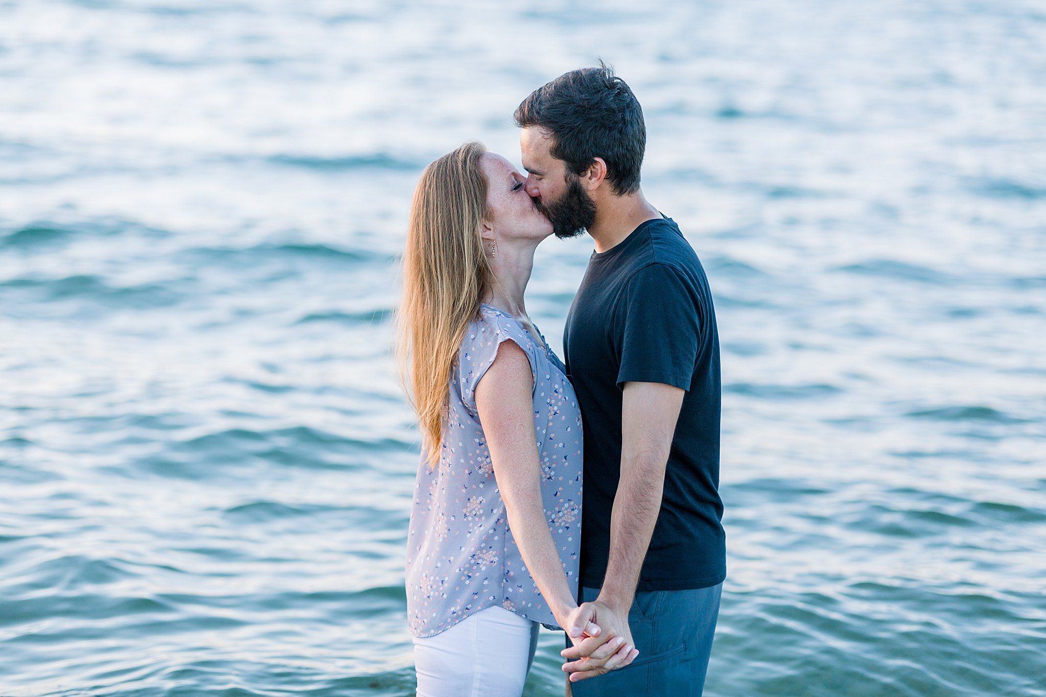 Couple kisses while playing in Lake Michigan during Peterson Beach Sleeping Bear Dunes engagement session.