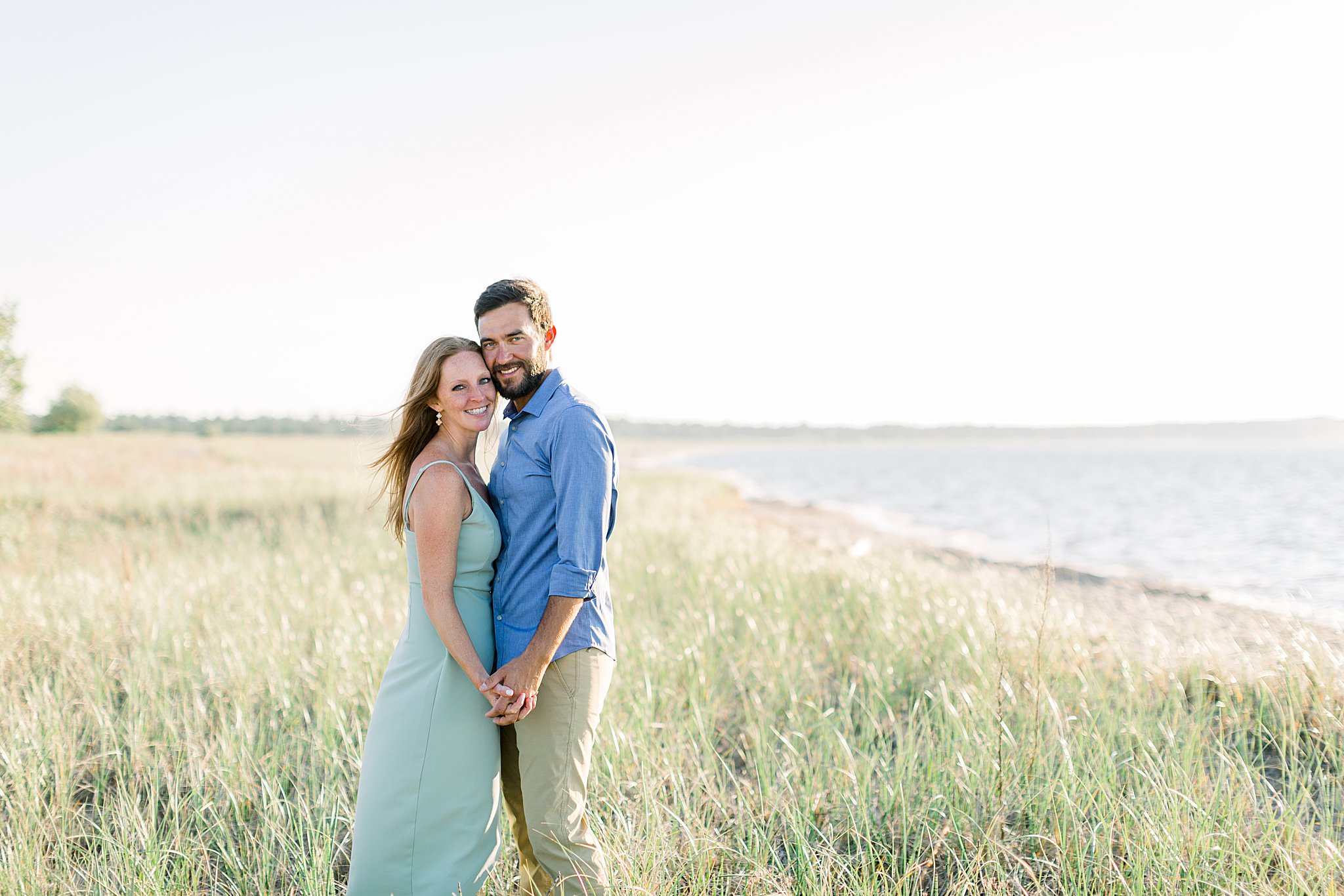 Bride and groom stand in wavy Lake Michigan grass during Peterson Beach Sleeping Bear Dunes engagement session.