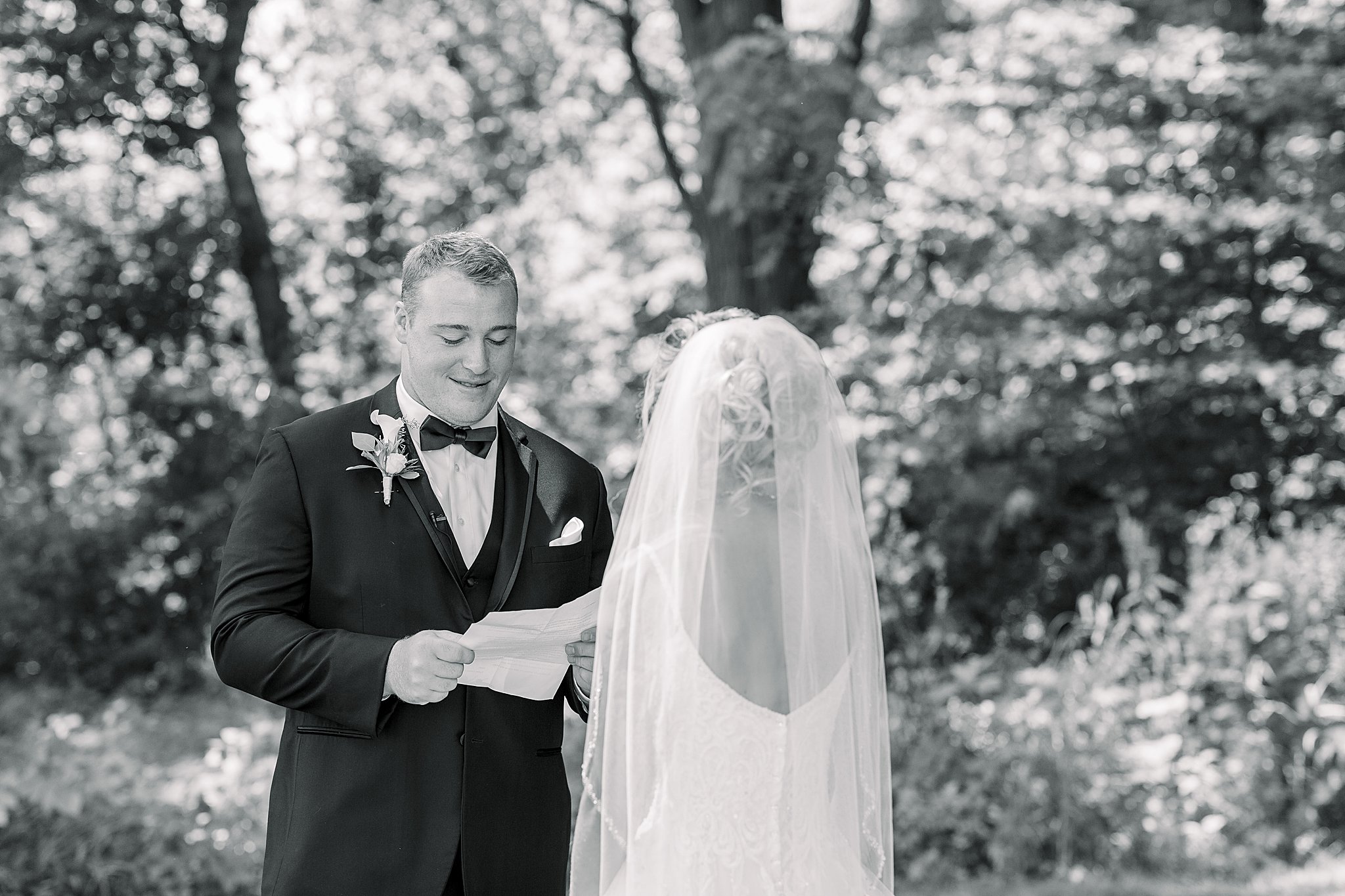 Groom reads letter to bride during first look at Post Family Farm Wedding