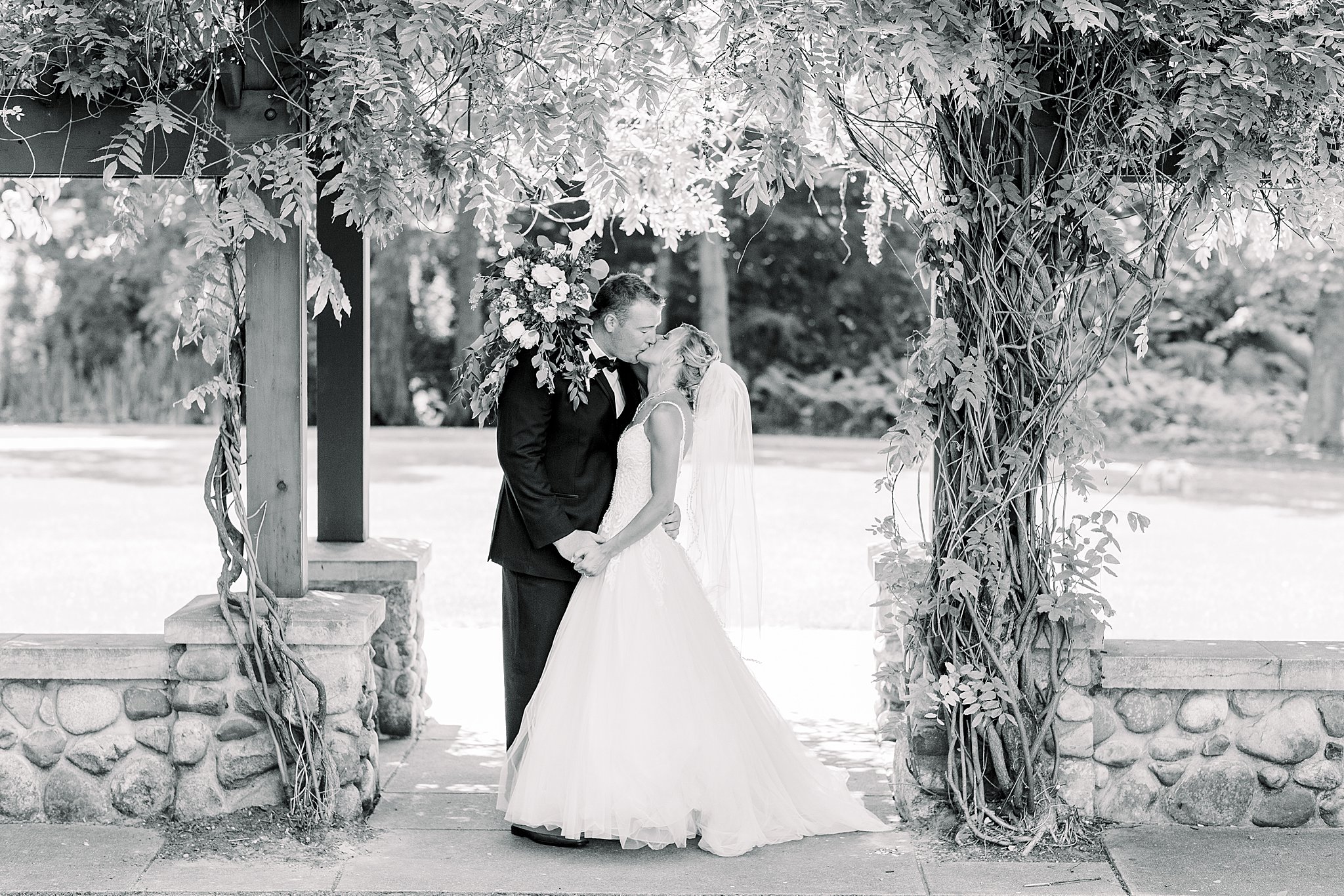 Bride and groom kiss under arbor during Post Family Farm Wedding