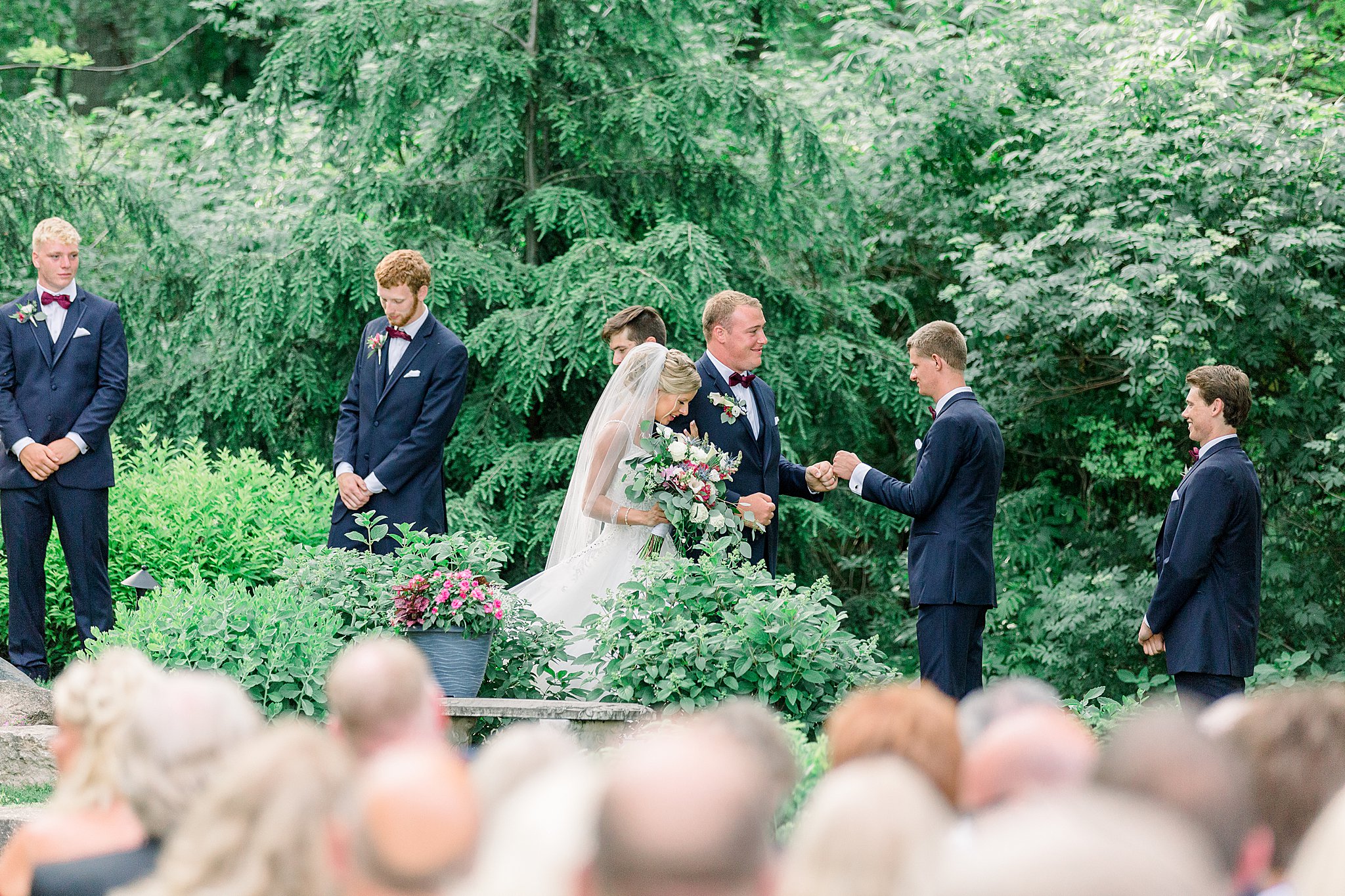 Groom fist bumps groomsman while leaving ceremony after Post Family Farm Wedding