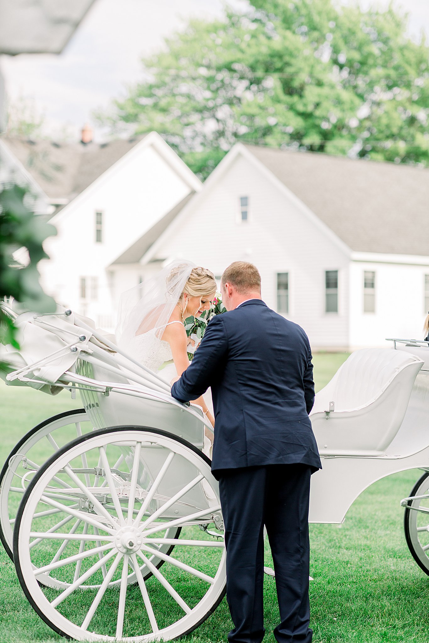 Groom helps bride into horse drawn carriage after ceremony during Post Family Farm Wedding