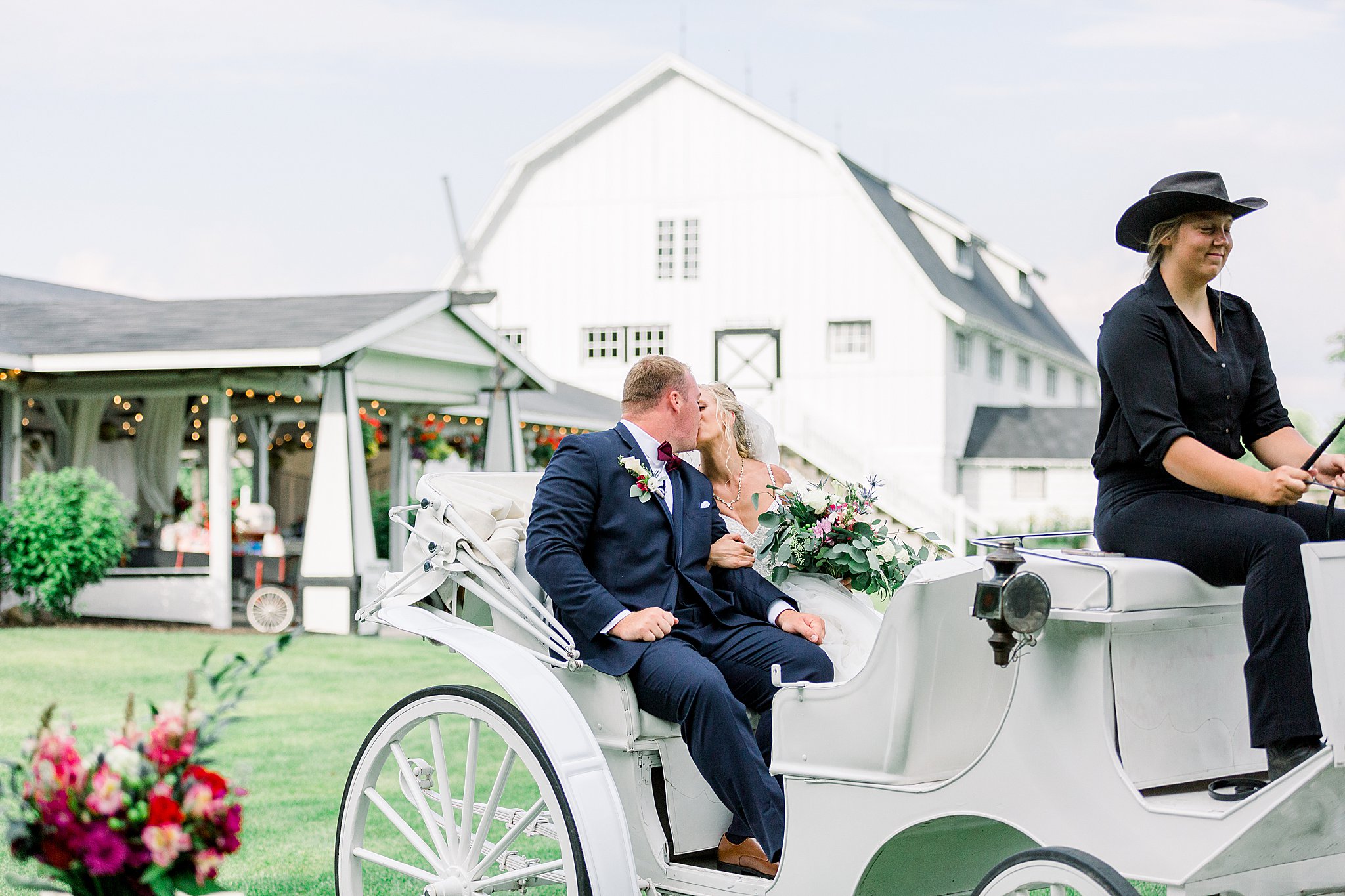 Bride and groom kiss while leaving ceremony in horse drawn carriage at Post Family Farm Wedding