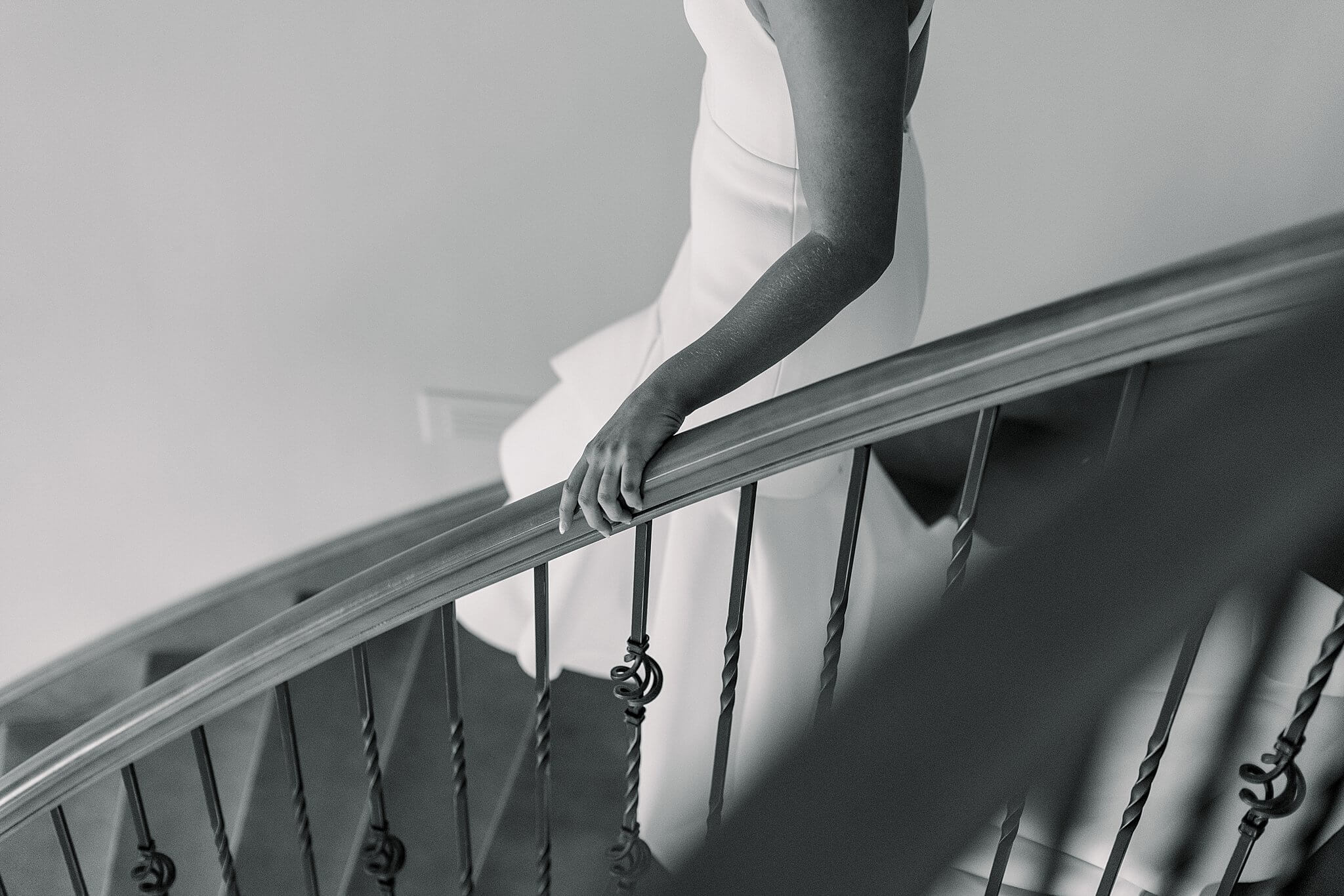 Black and white image of bride coming down spiral staircase during her summer backyard wedding in Northern Michigan.