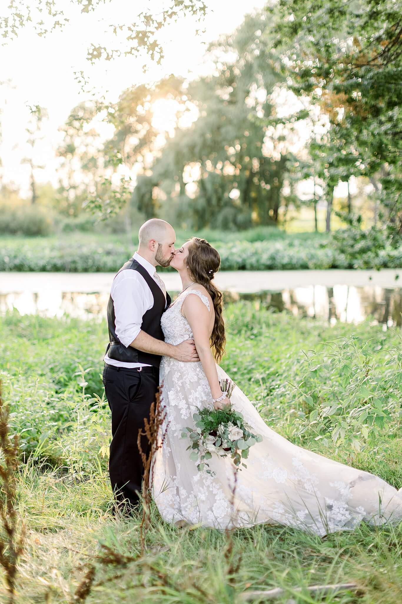 Bride and groom kiss during sunset at Michigan Summer Backyard Wedding