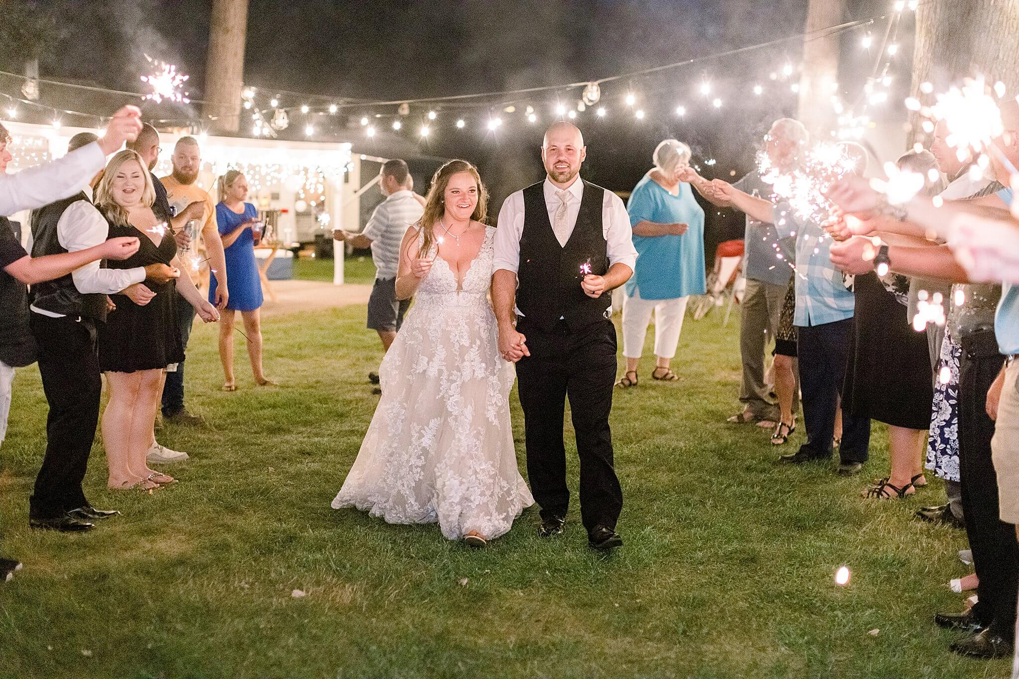 Bride and groom run through sparkler exit line during Michigan Summer Backyard Wedding