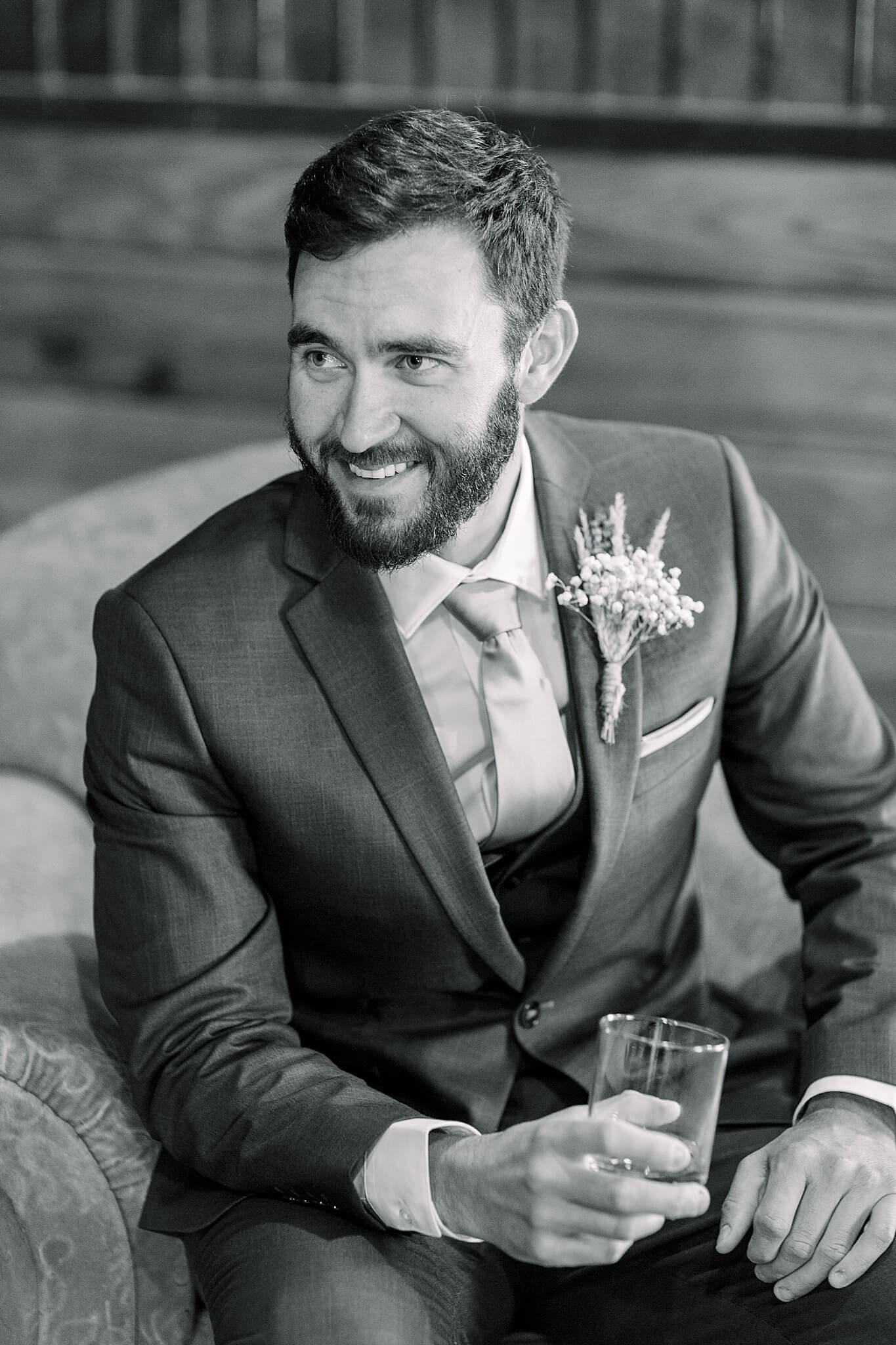 Black and white portrait of groom drinking whiskey at Crooked Creek Ranch wedding.