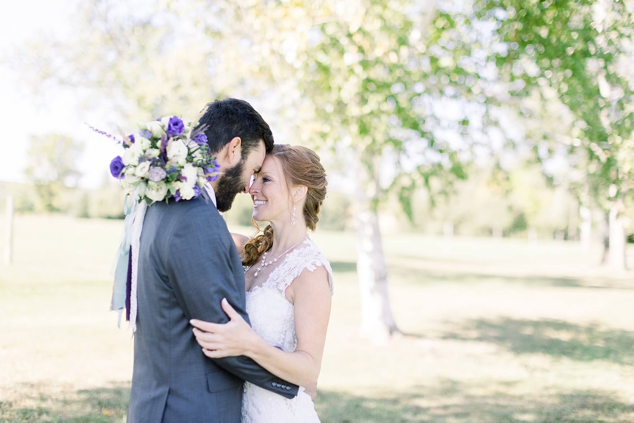Bride and groom smile while touching foreheads during Crooked Creek Ranch wedding portraits.