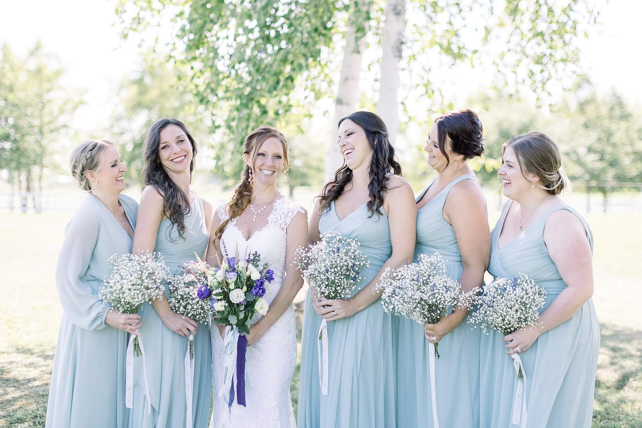 Bride and bridesmaids laughing at each other during Crooked Creek Ranch wedding.