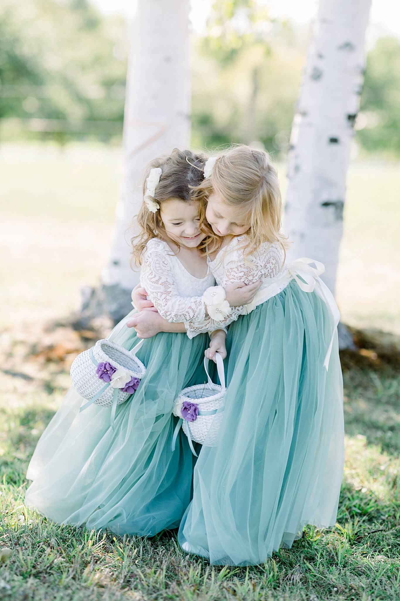 Flower girls hug each other and giggle during Crooked Creek Ranch wedding.