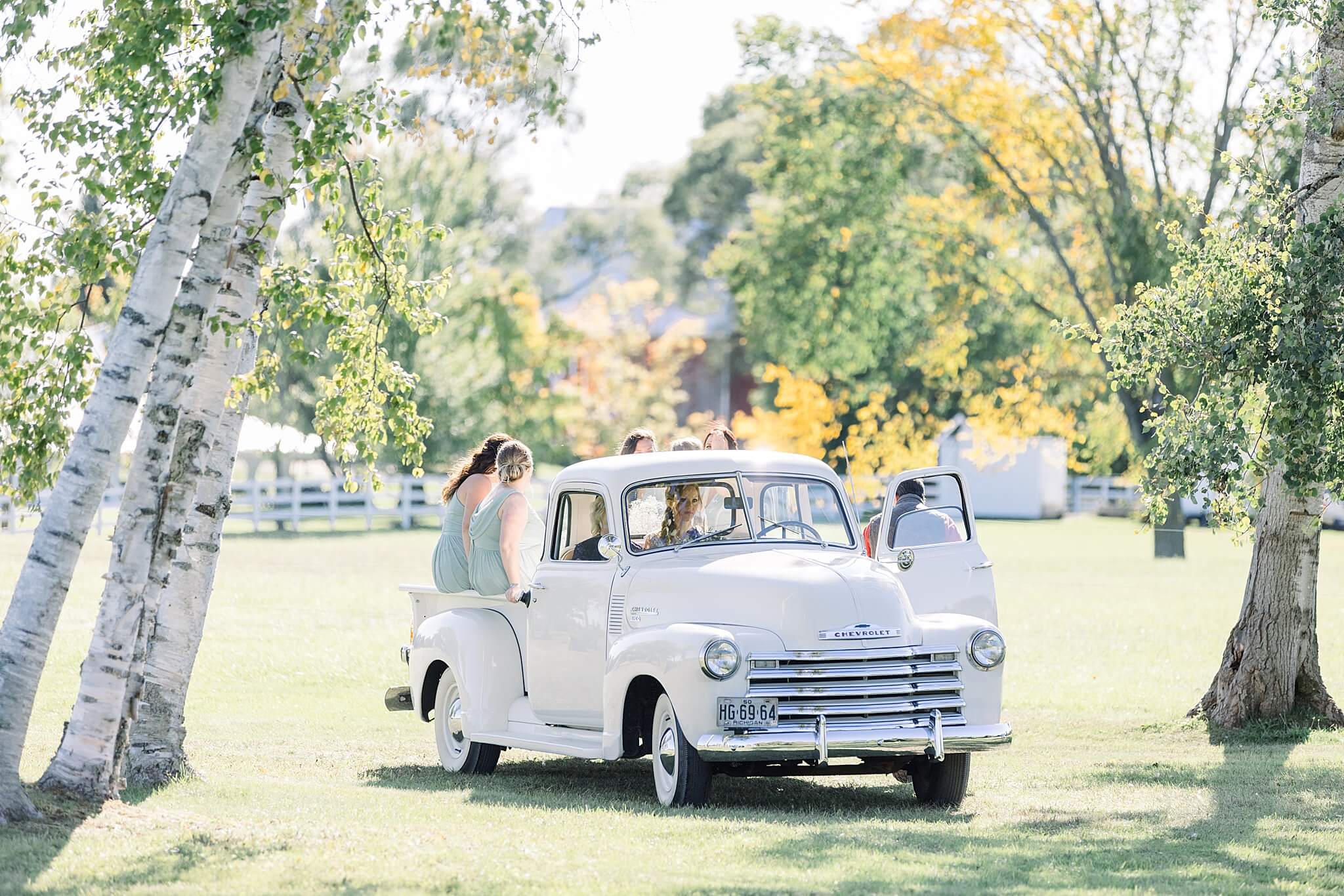 Bride and bridesmaids enter Crooked Creek Ranch wedding ceremony in classic, vintage white truck. 