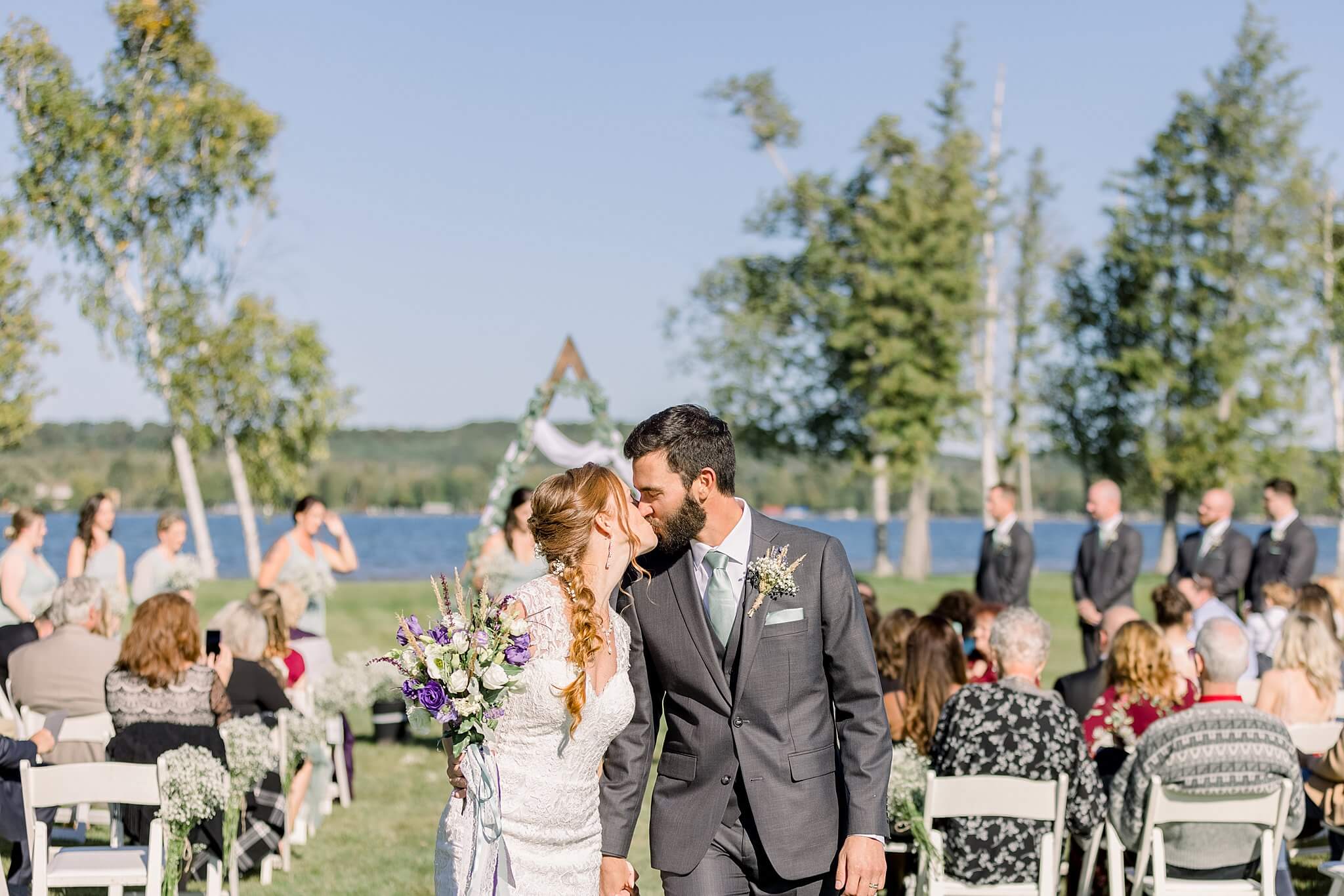 Bride and groom share kiss while leaving wedding ceremony at Crooked Creek Ranch wedding.