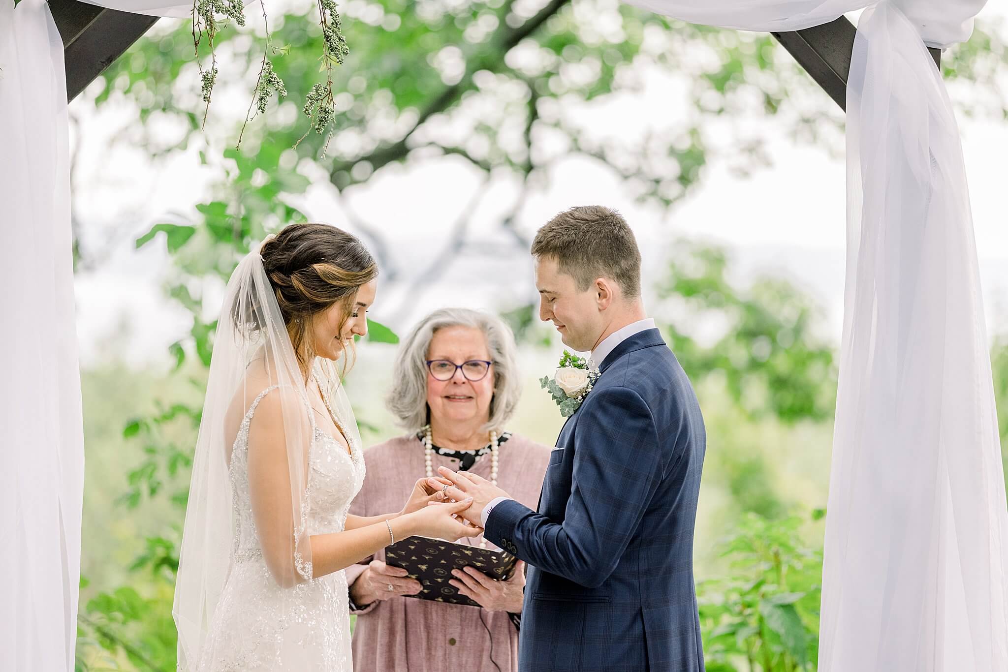 Bride places ring on groom's finger during their wedding ceremony for their Intimate Northern Michigan Wedding.