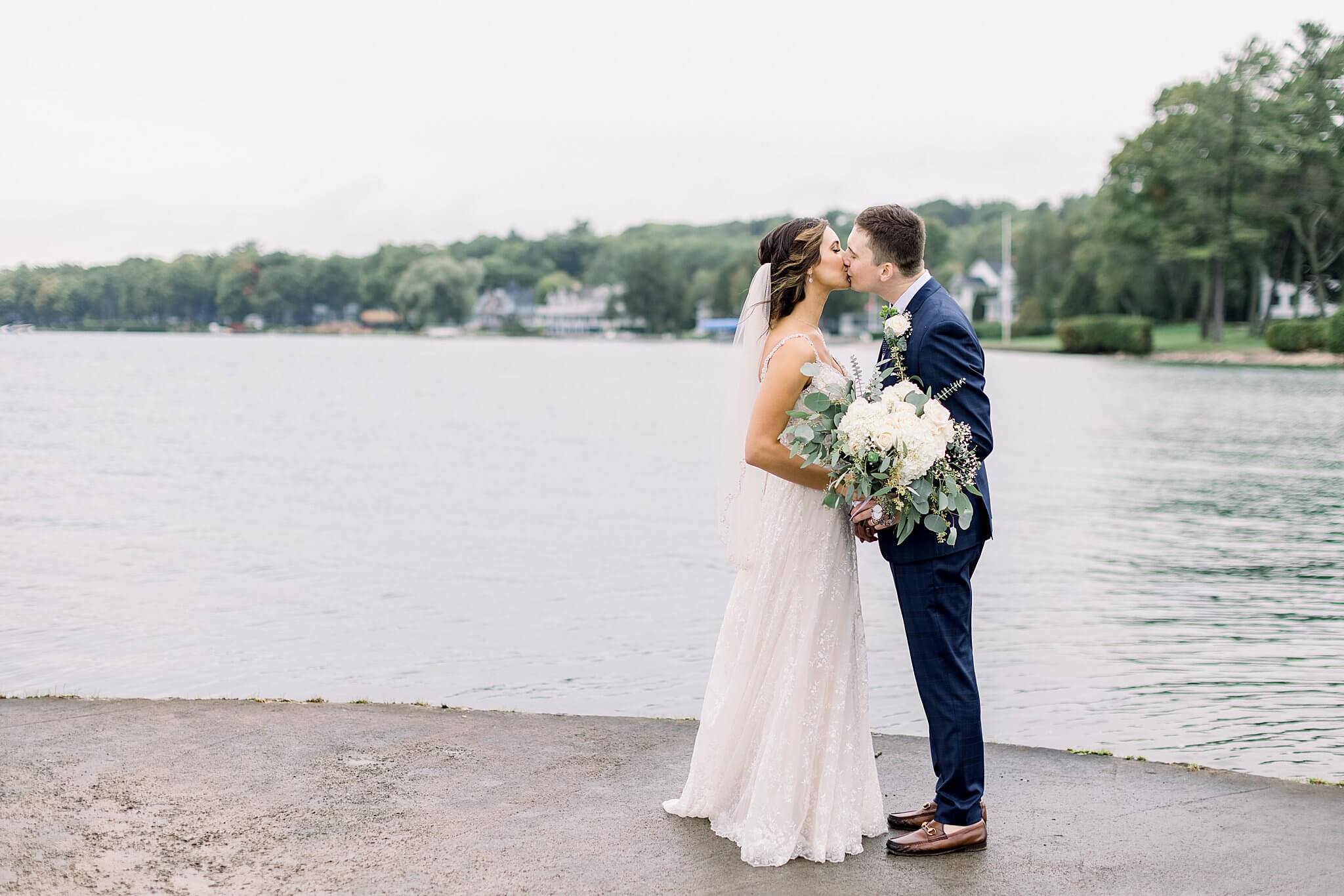 Bride and groom share a kiss on the pier in Harbor Springs, Michigan during Intimate Northern Michigan Wedding.