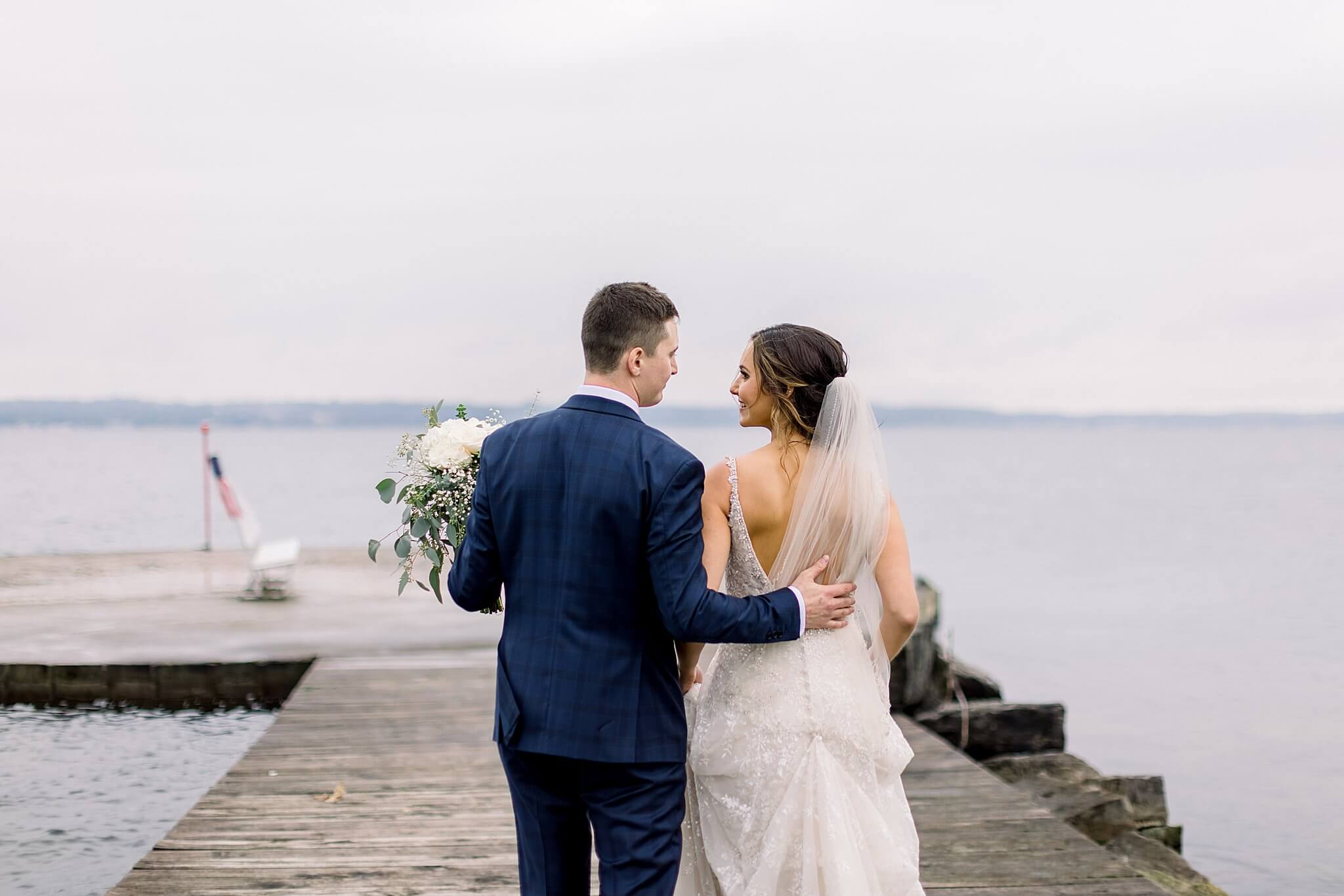 Bride and groom walk along pier on overcast day during Intimate Northern Michigan Wedding.