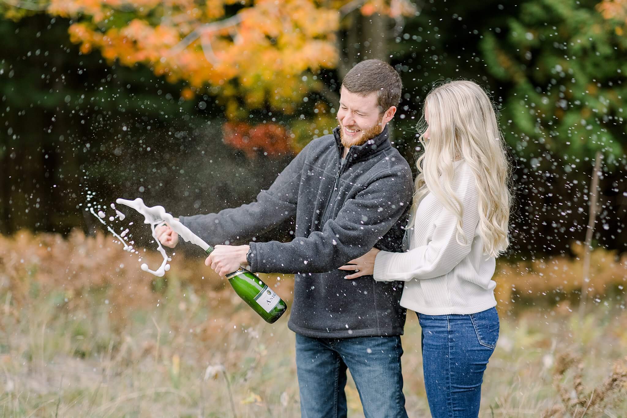 Bride and groom pop champagne during M22 Fall Engagement Session in Northern Michigan.