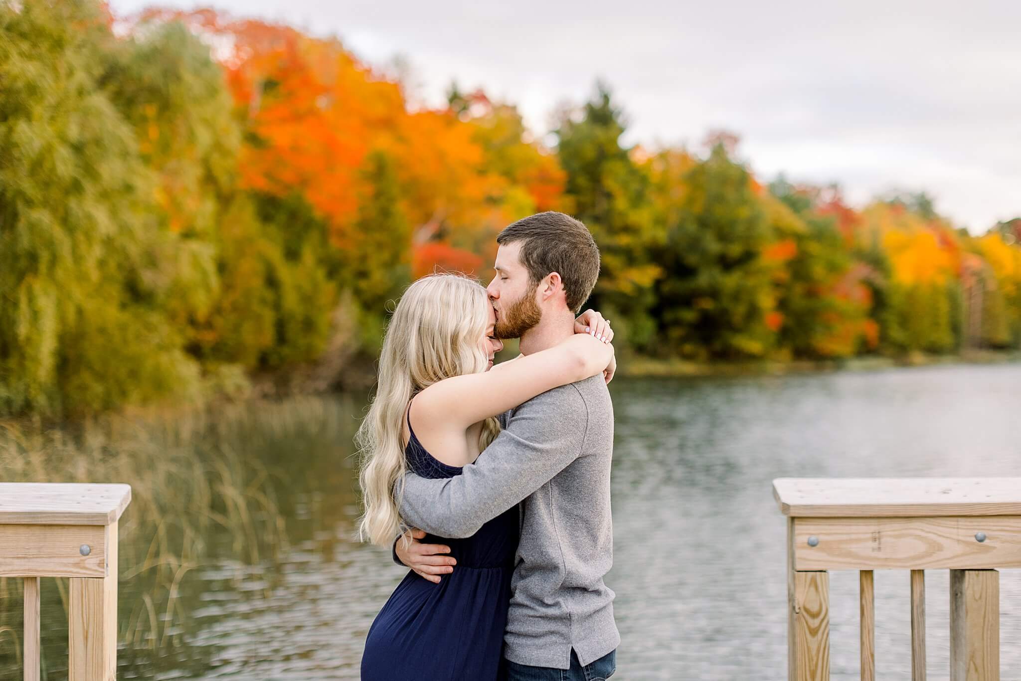 Bride and groom kiss on dock during M22 Fall Engagement Session in Northern Michigan.