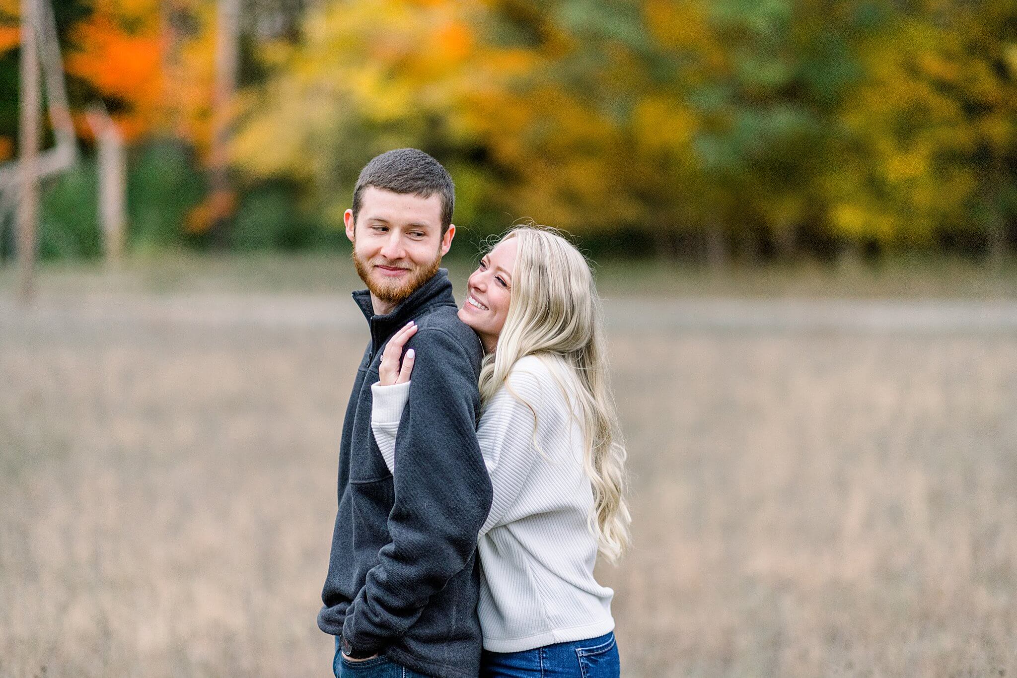 Bride smiles at groom while hugging him during M22 Fall Engagement Session in Northern Michigan.