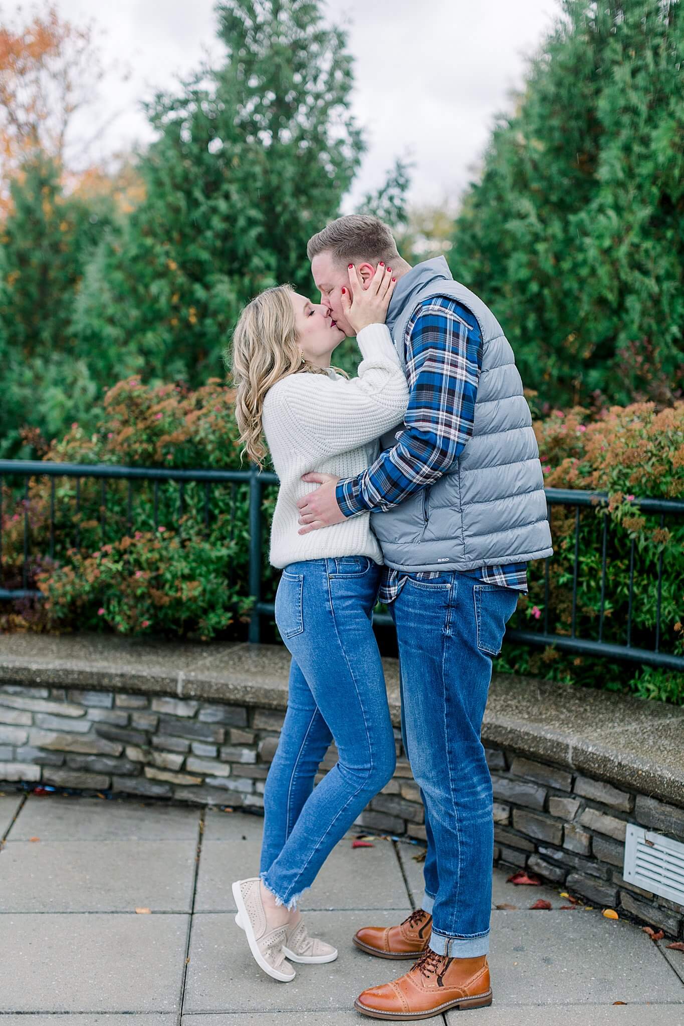 Bride kisses groom during rainy fall engagement session in Charlevoix, Michigan.
