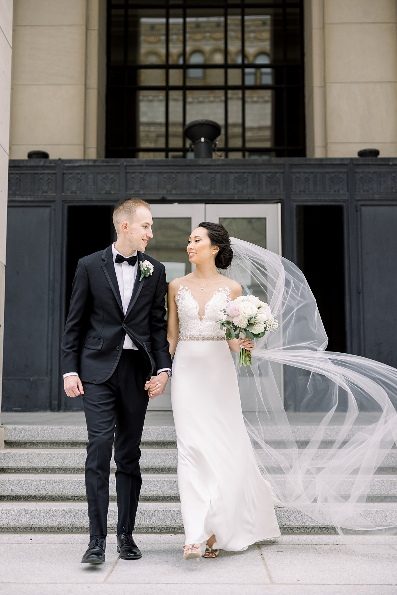 Bride and groom walk down Civic Center steps during elegant Grand Rapids wedding.