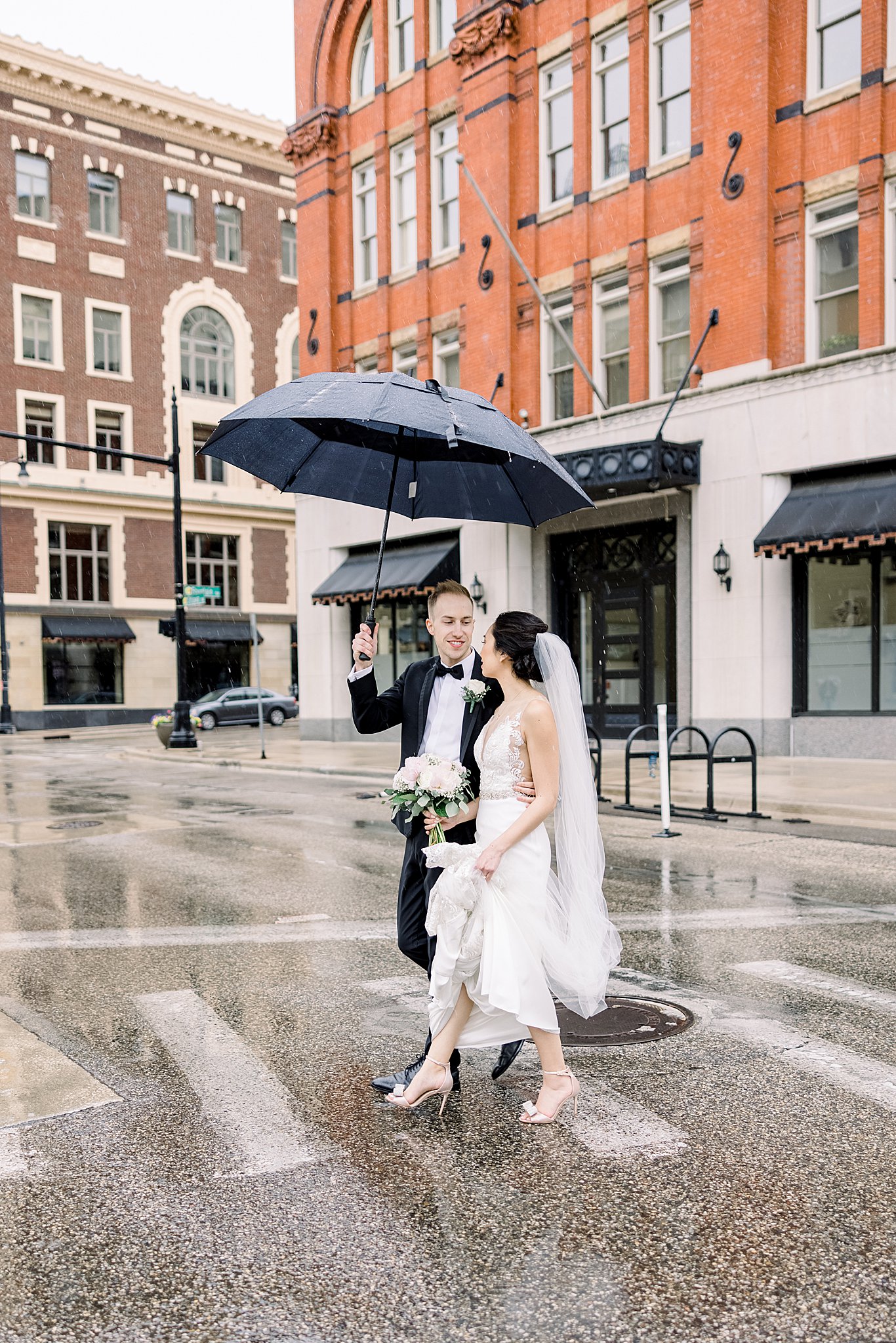 Bride and groom stroll in the rain downtown Grand Rapids.
