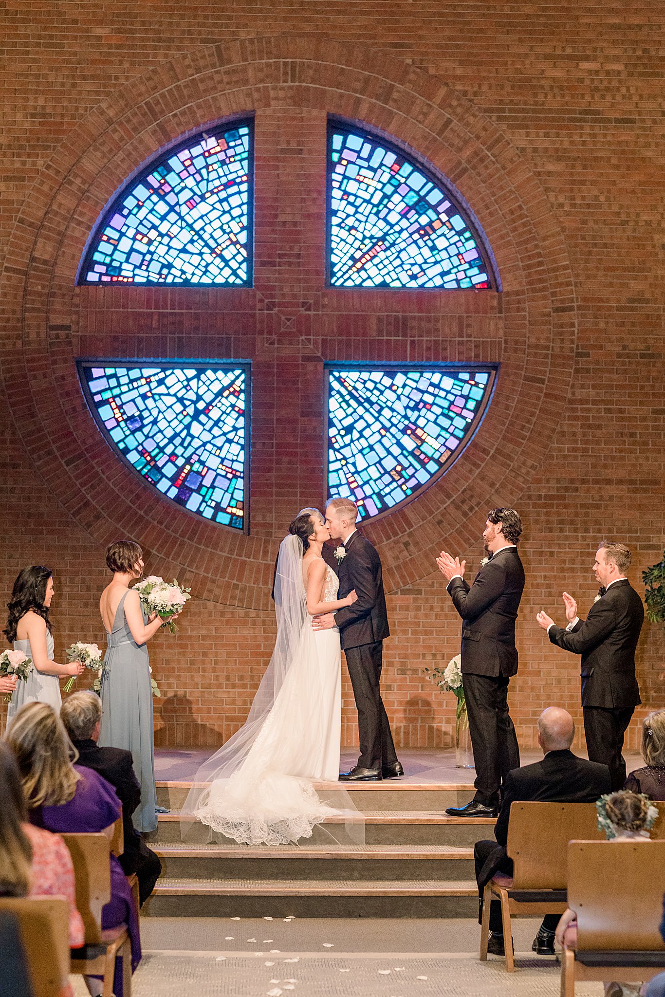 Bride and groom's first kiss at the church altar during elegant Grand Rapids wedding.