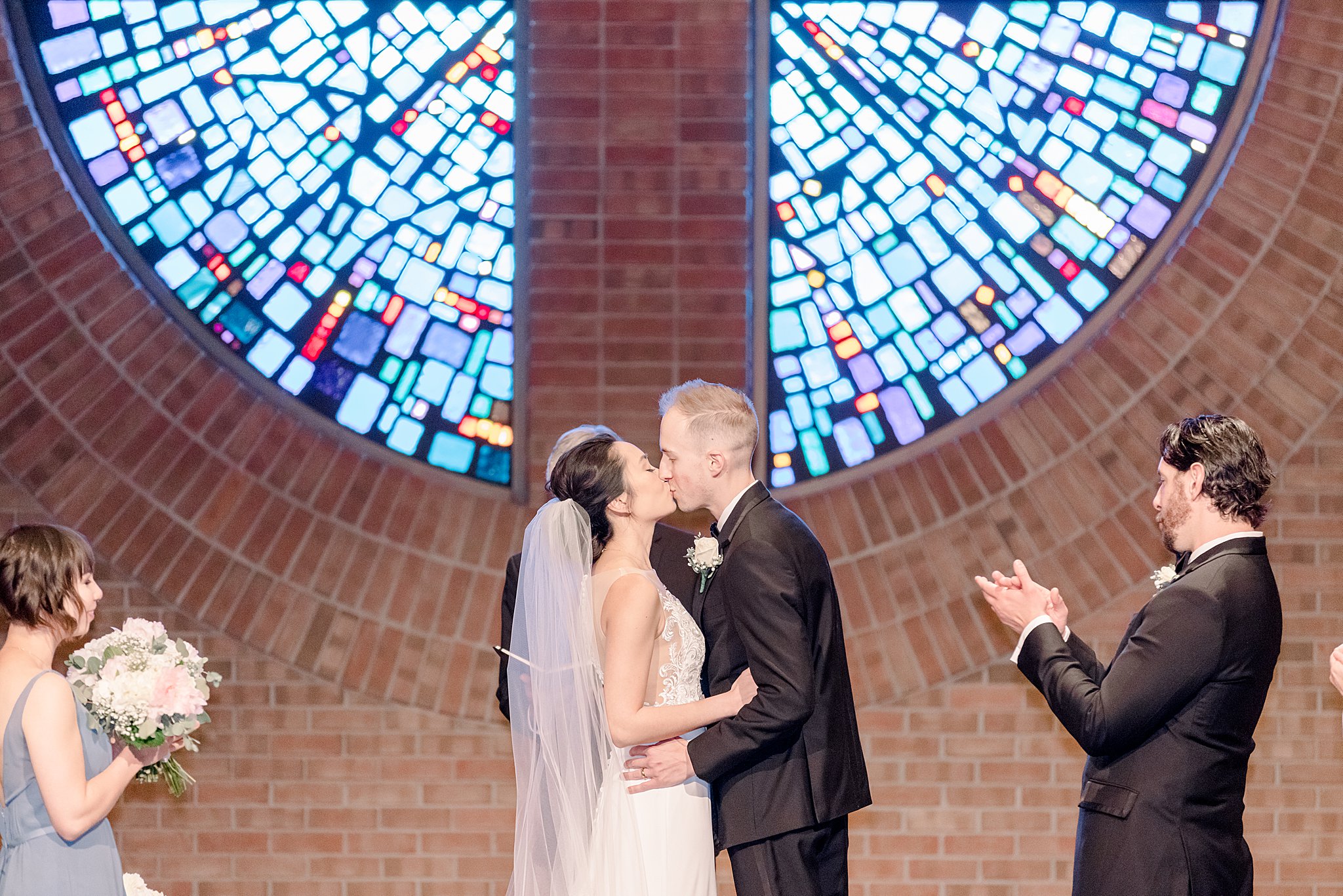 Bride and groom share first kiss at the altar during elegant Grand Rapids wedding.