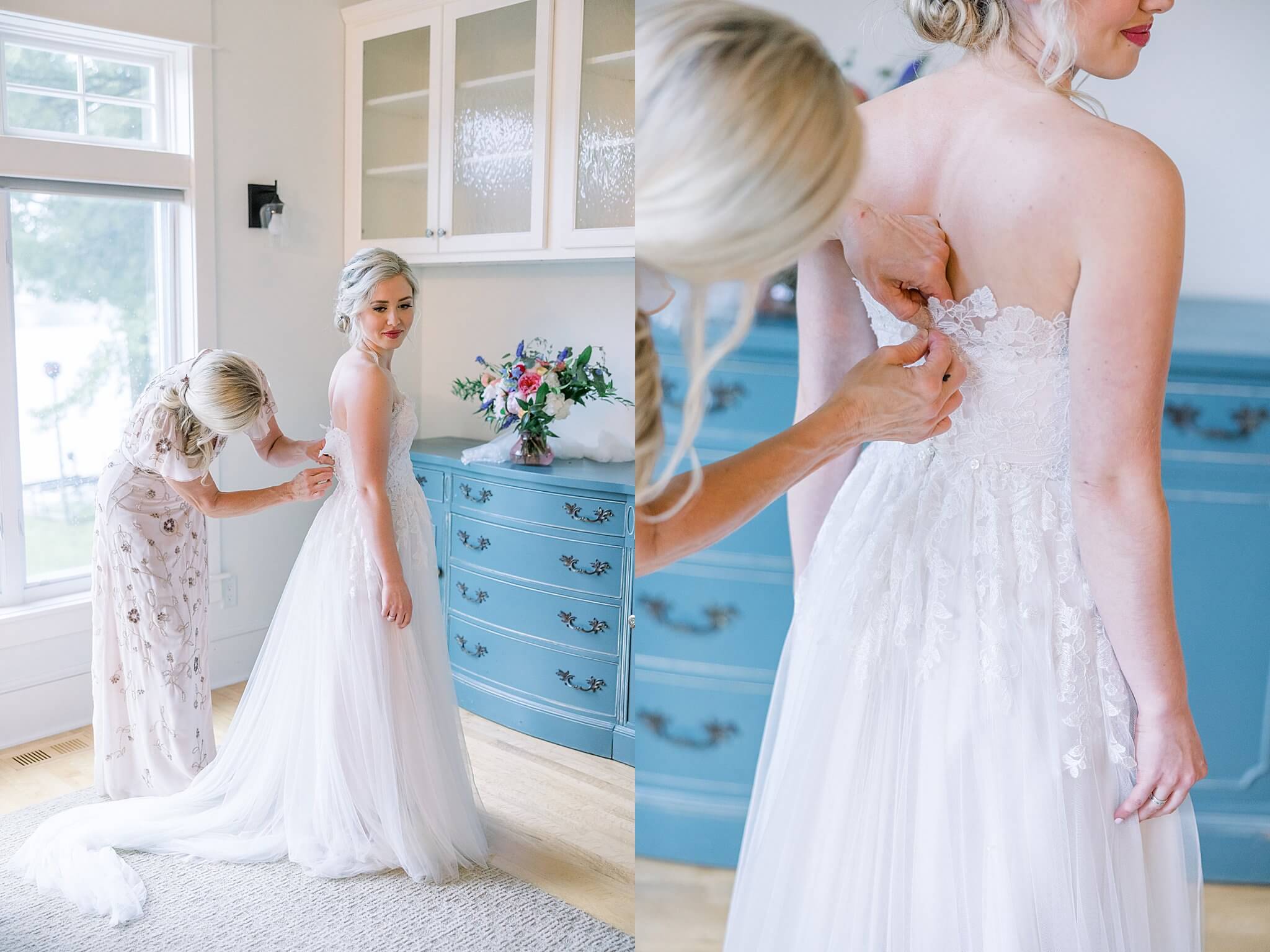 Mother of the bride helps fasten vintage lace dress for her daughter while she gets ready for her Traverse City wedding ceremony.