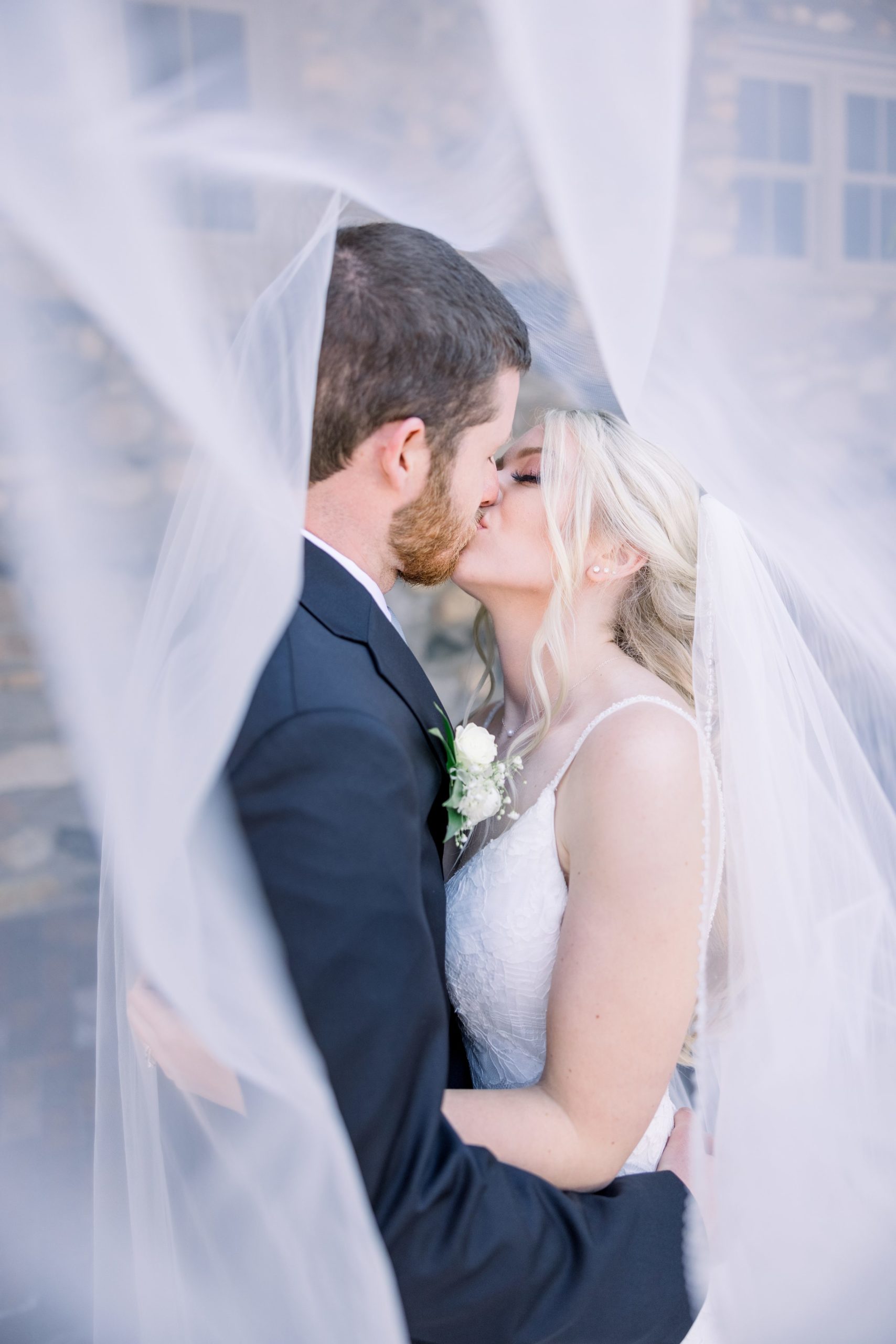 Bride and groom kiss under veil in the Queen's Courtyard at Castle Farms. 