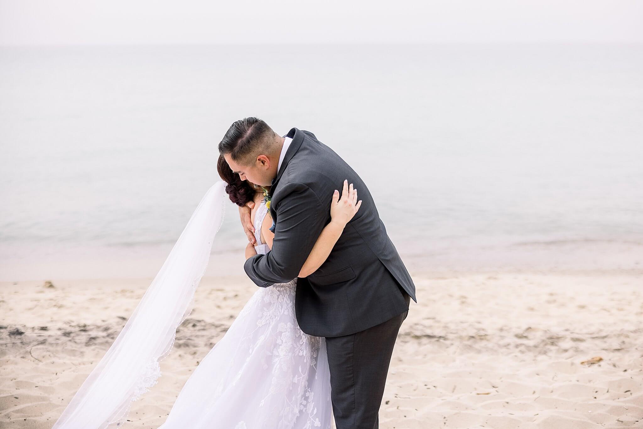 Groom hugs his bride during their first look before Elberta Life Saving Station wedding day.